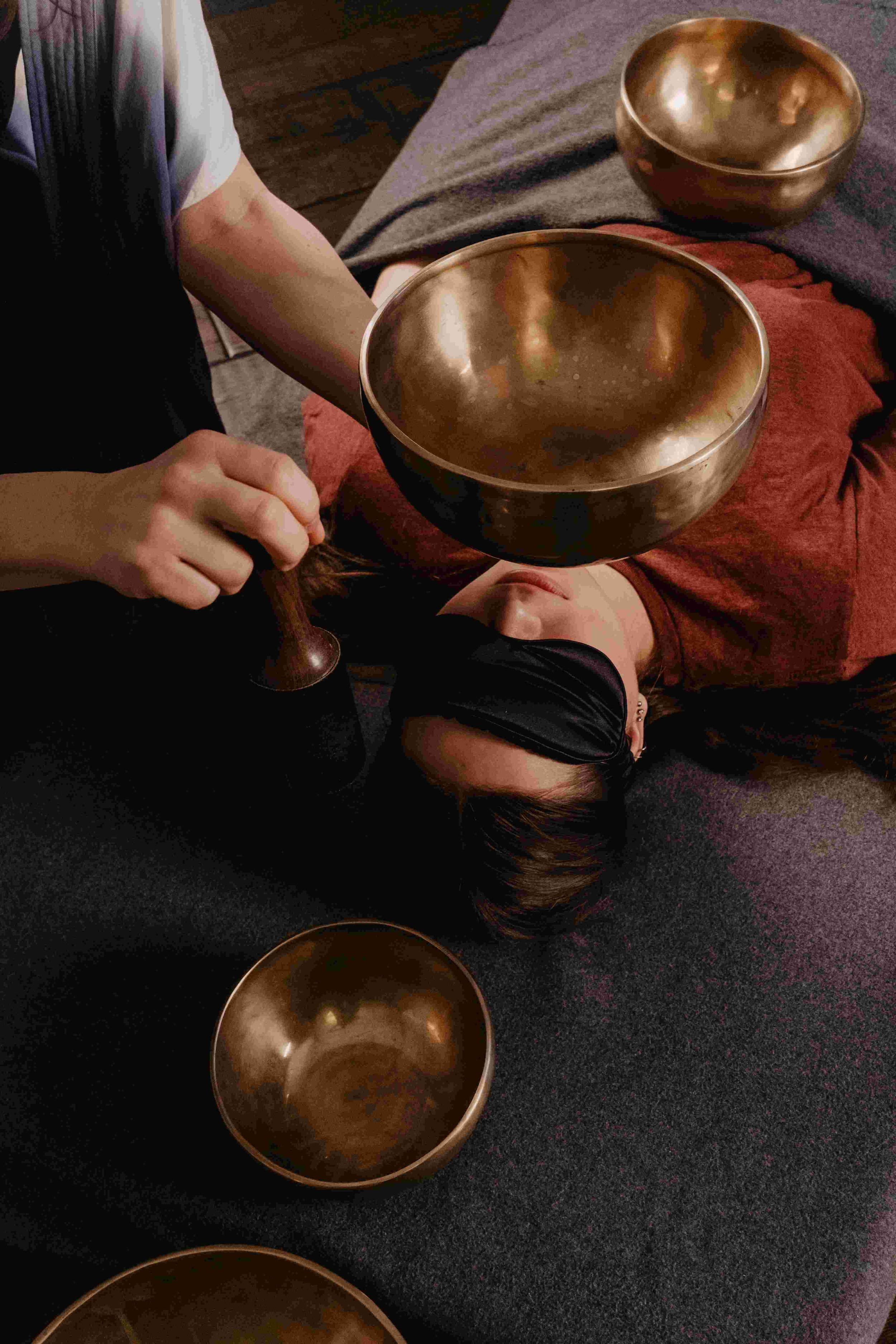 A person receiving a sound therapy healing session with bronze singing bowls captured by Aces and Oak.