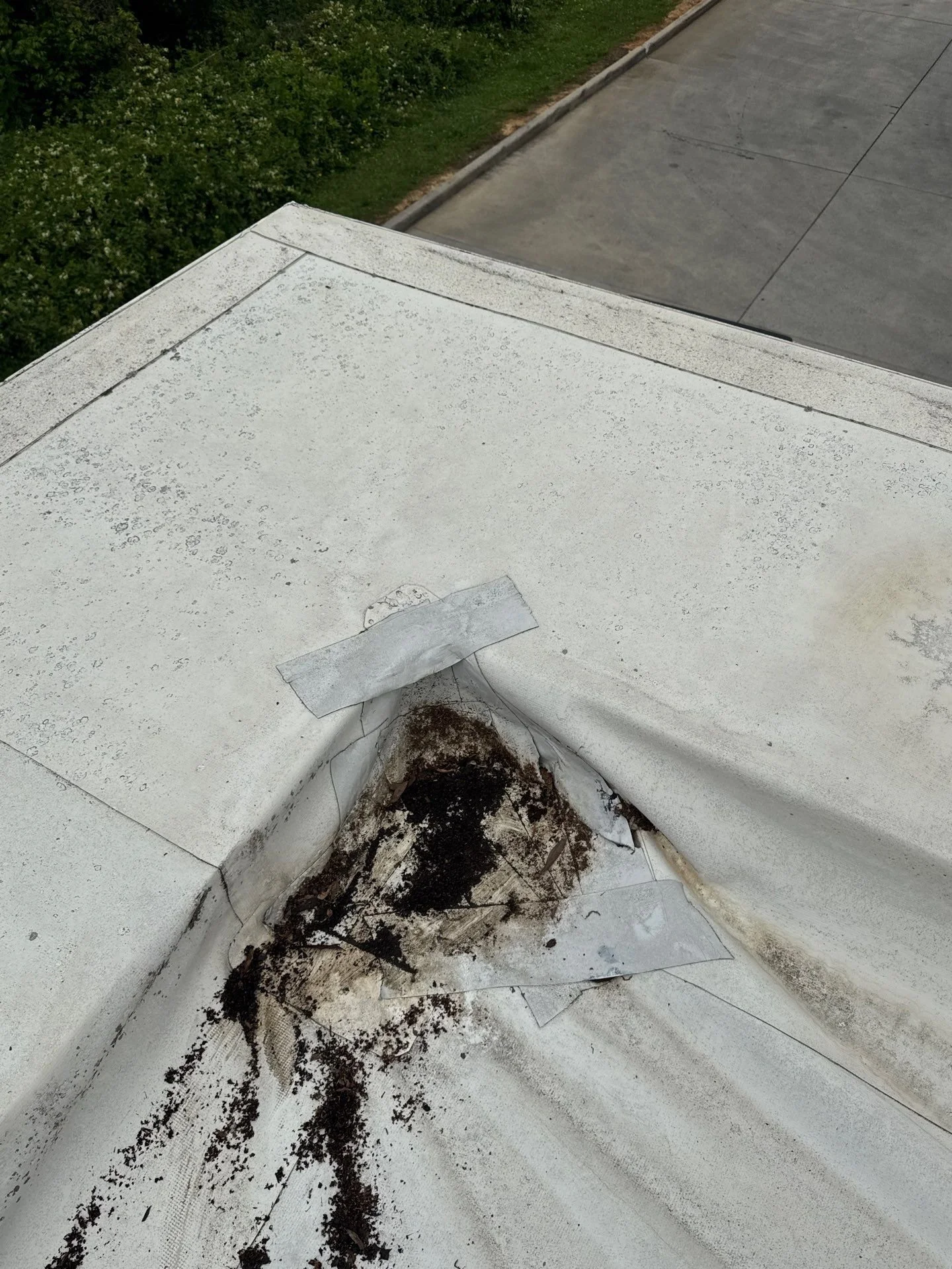 A close-up view of severe wind and water damage on a commercial TPO flat roof in Rome, Georgia, showing a torn membrane and exposed underlayment that Oak Ridge Roofing's veteran-led team is preparing to repair.