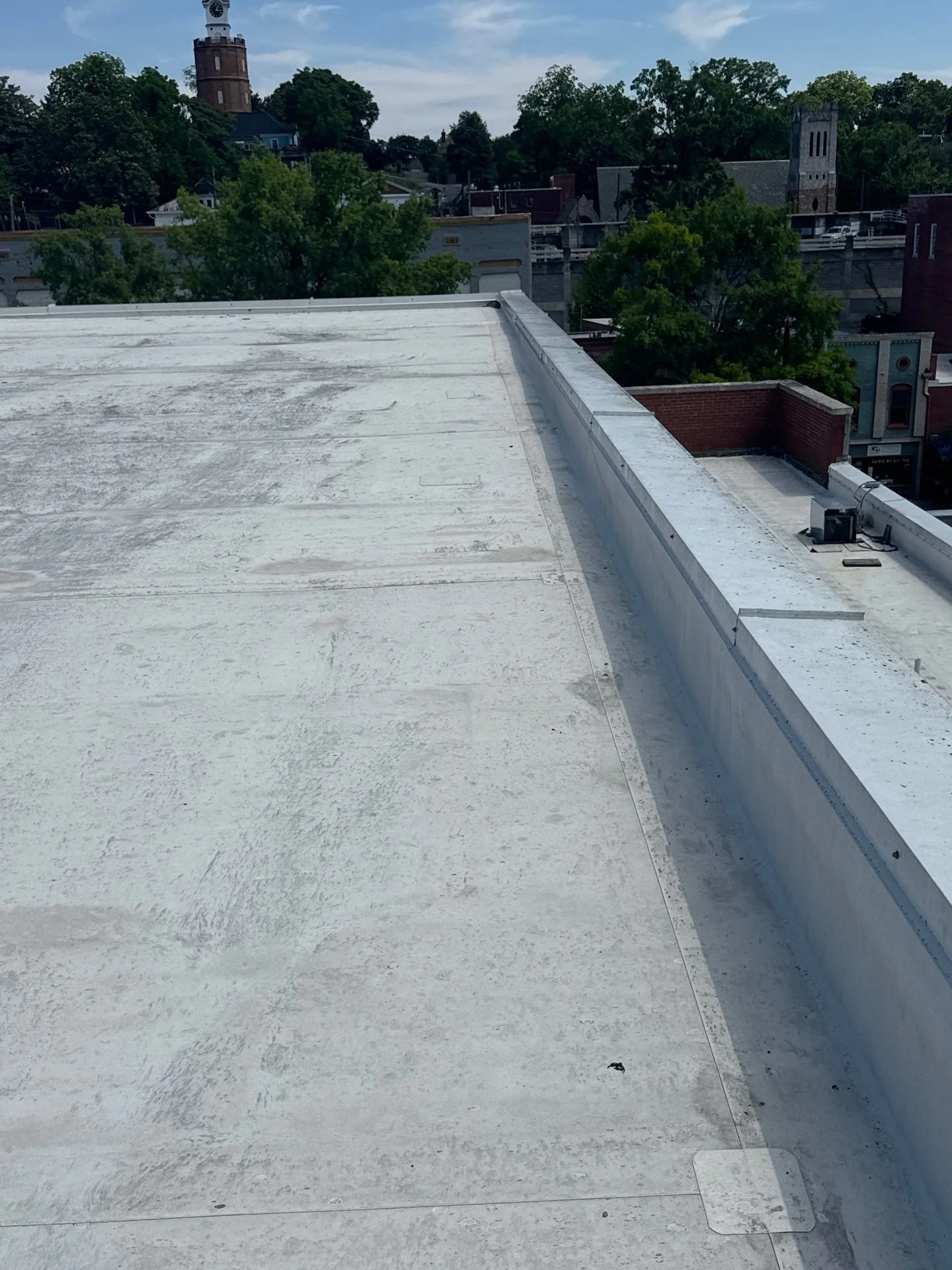 A wide view of a highly reflective commercial TPO flat roof inspected by Oak Ridge Roofing, overlooking the historic downtown district of Rome, Georgia. Our veteran-led team specializes in elite, energy-efficient commercial roofing solutions that sec