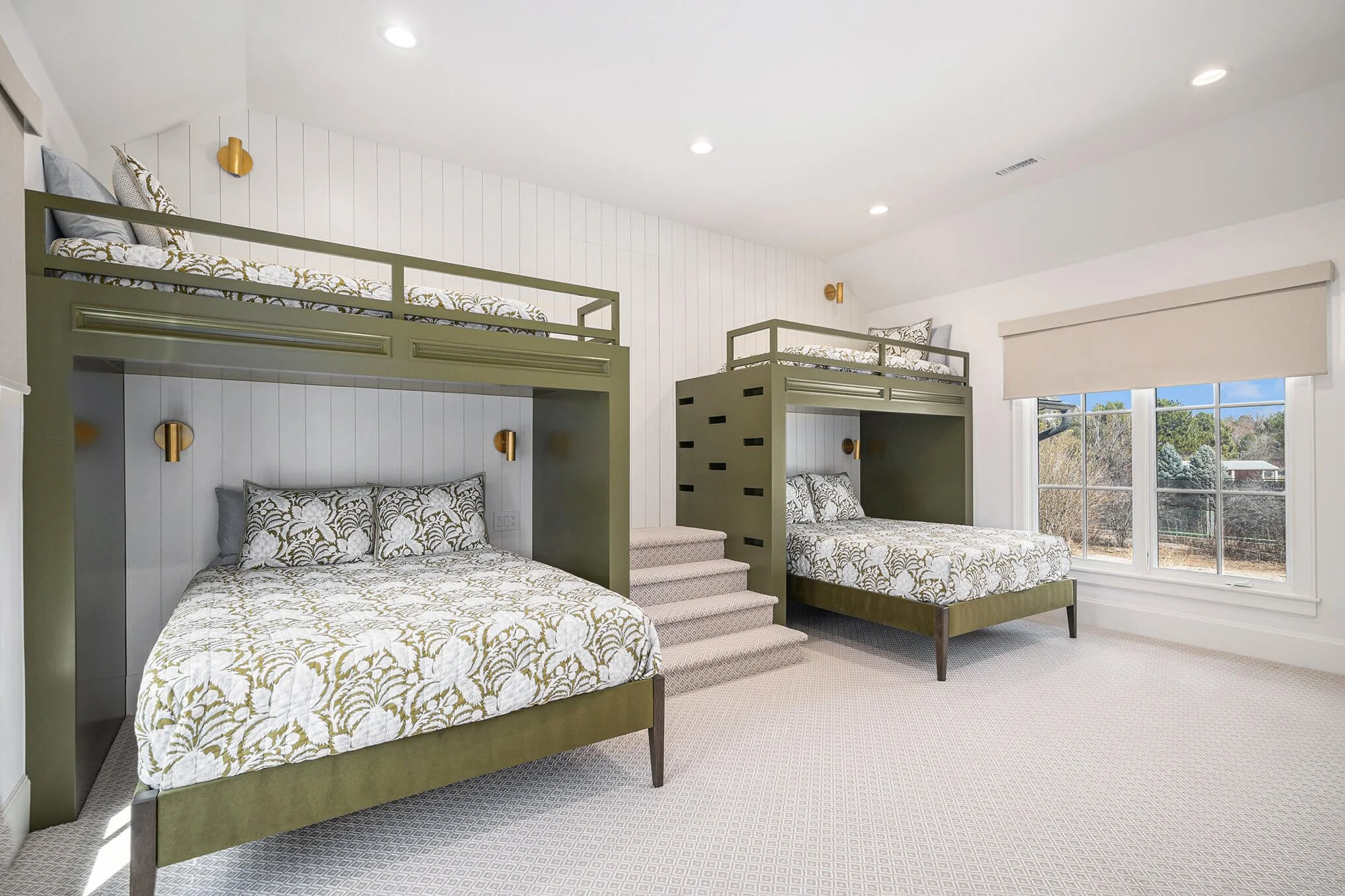 Bedroom with two olive green bunk beds, each with twin beds on top and full beds on the bottom, patterned bedding, carpeted floor, and a large window with a view.