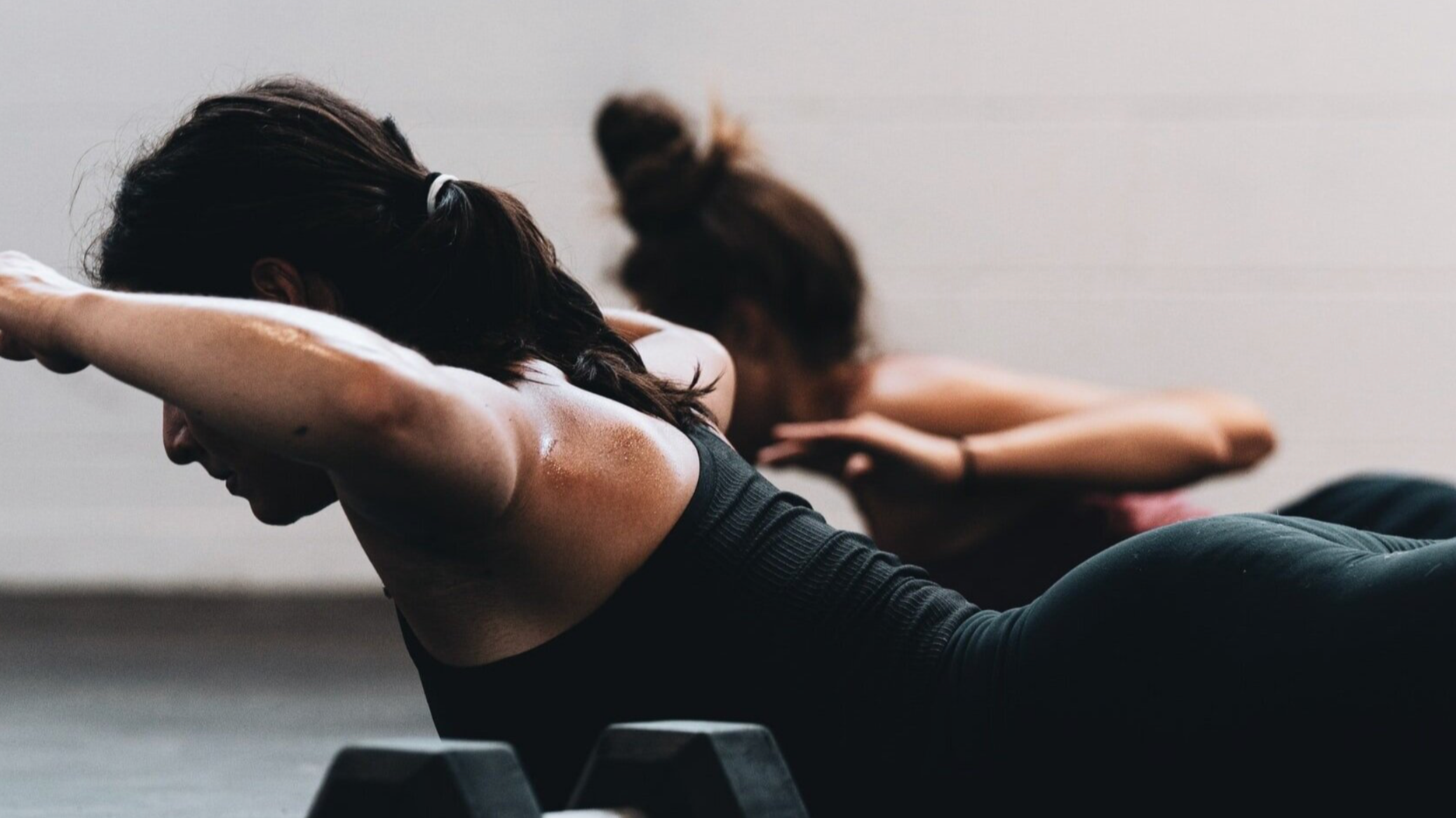 Two women doing a superman to strengthen a dancer's upper back.