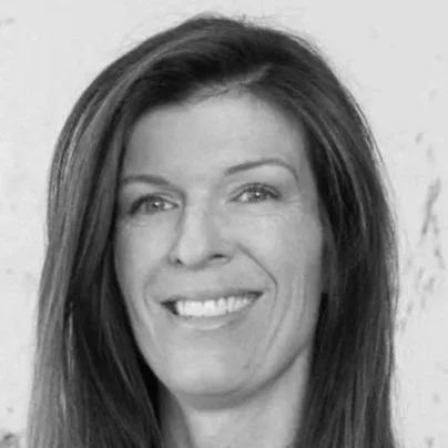 Black and white headshot of a woman smiling with straight, shoulder-length hair.