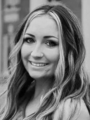 Black and white portrait of a smiling woman with long hair.