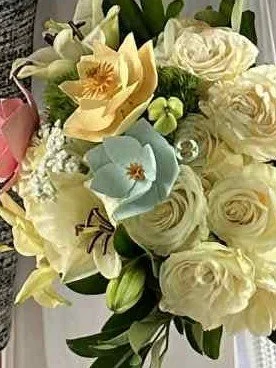 The finished and painted magnolias in the center of a bridal bouquet.  The magnolias have been painted pink, yellow, and blue.