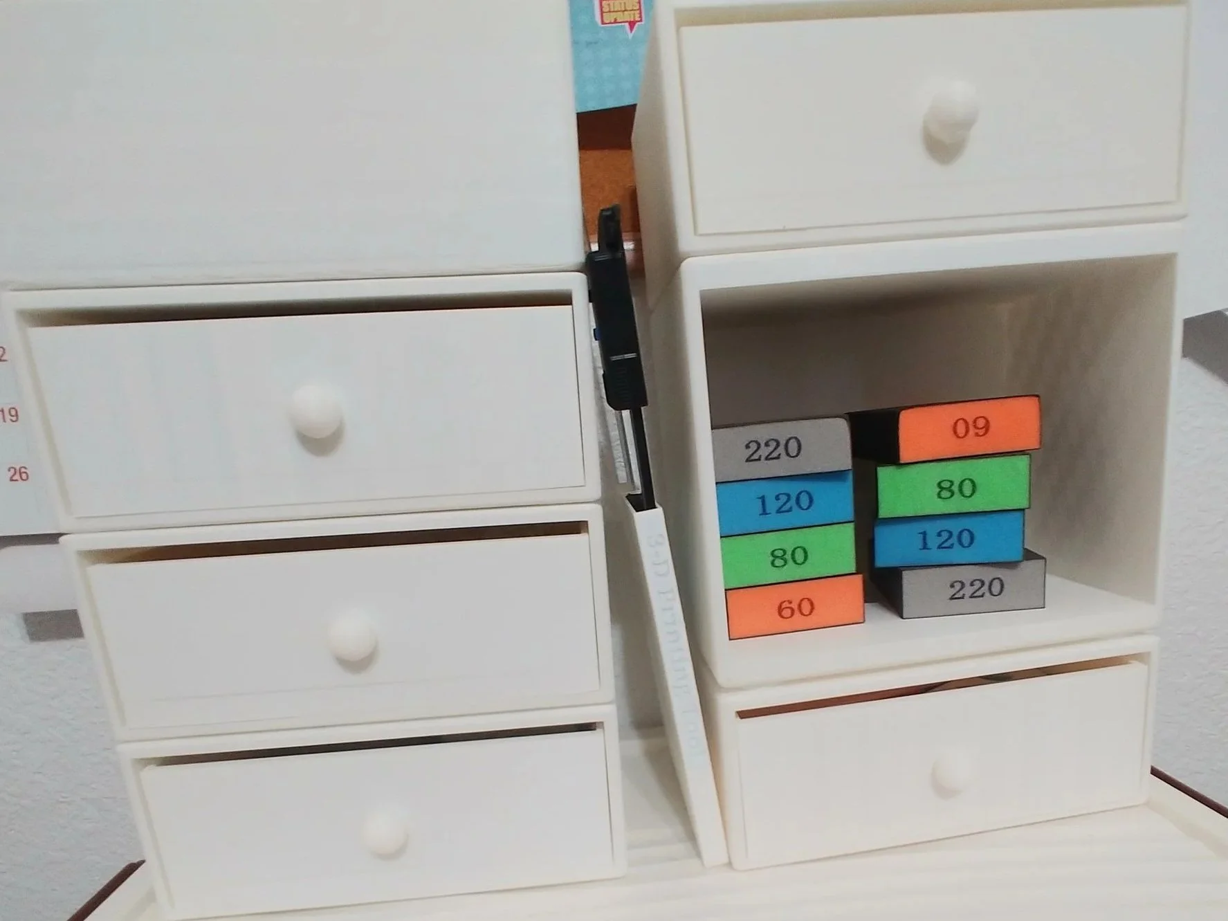 Two 3D printed towers with some drawers, cubbies, and a tray.  A caliper and ruler holder is between them, and colorful sponges sit in a cubby.