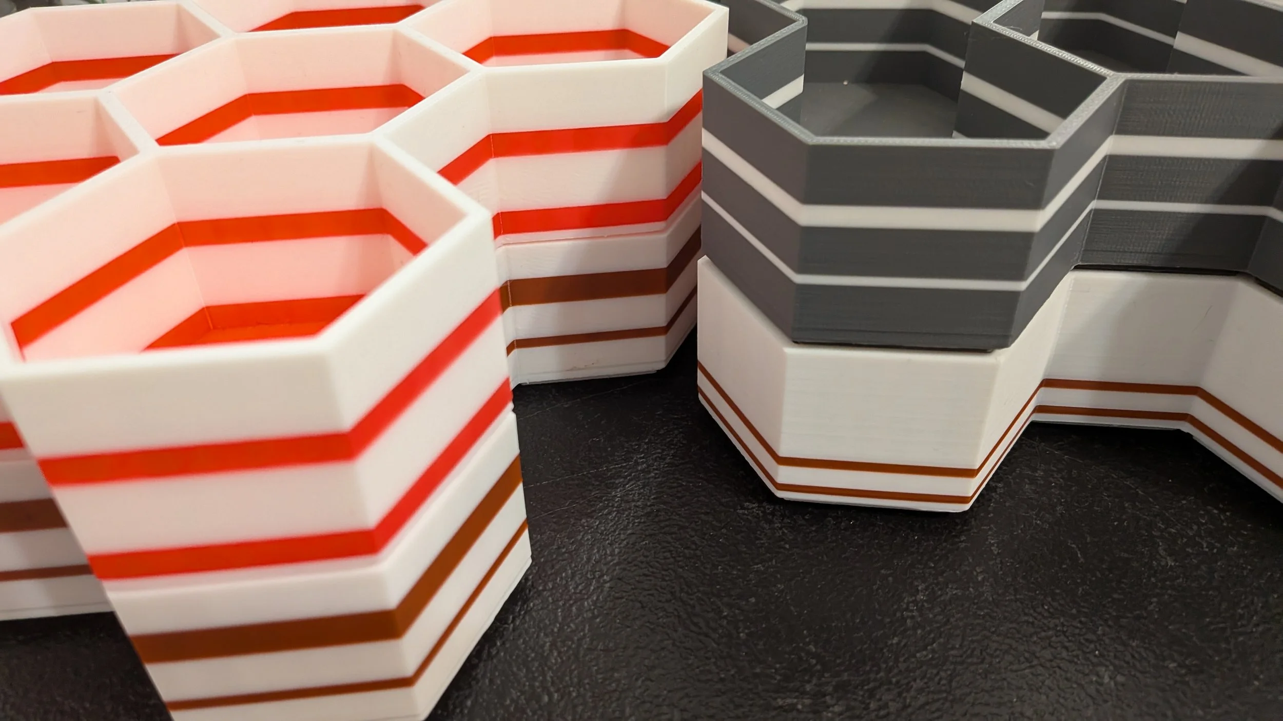 A quarter-circle cutout view of a set of hexagon-based storage bins.  The bins are made using color-swap techniques, so they have thin stripes of color.