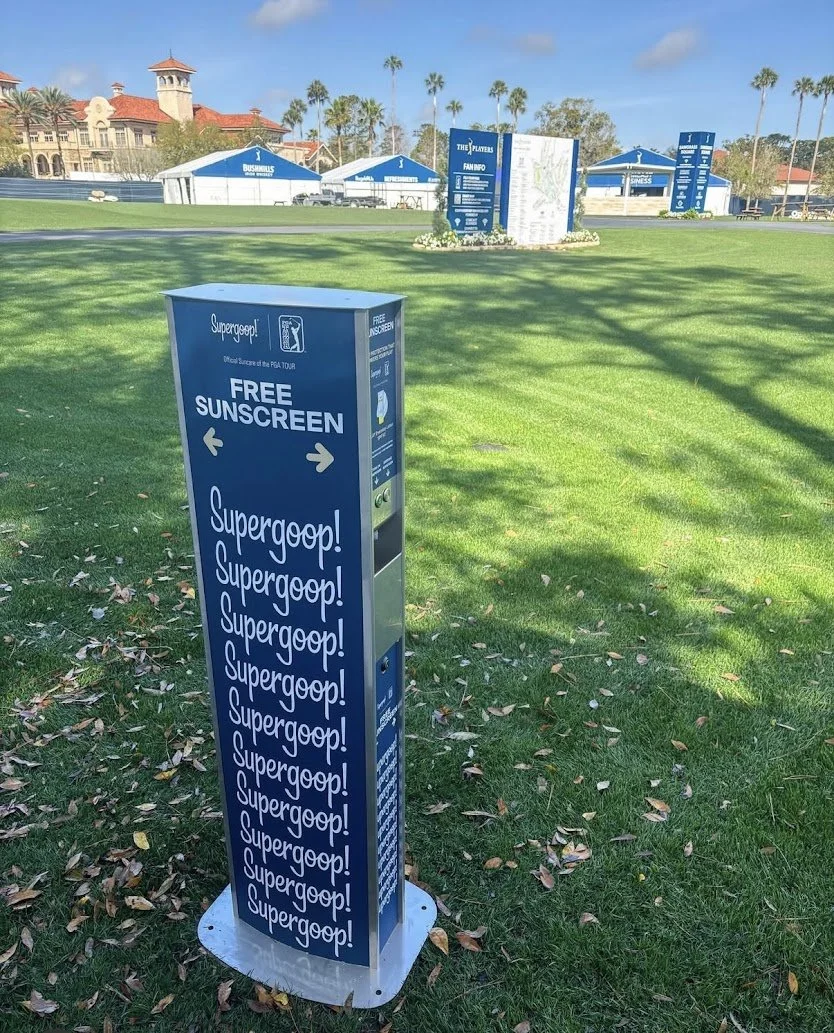 Supergoop branded sunscreen dispenser at THE PLAYERS Championship providing free sunscreen for fans at major outdoor sporting events.