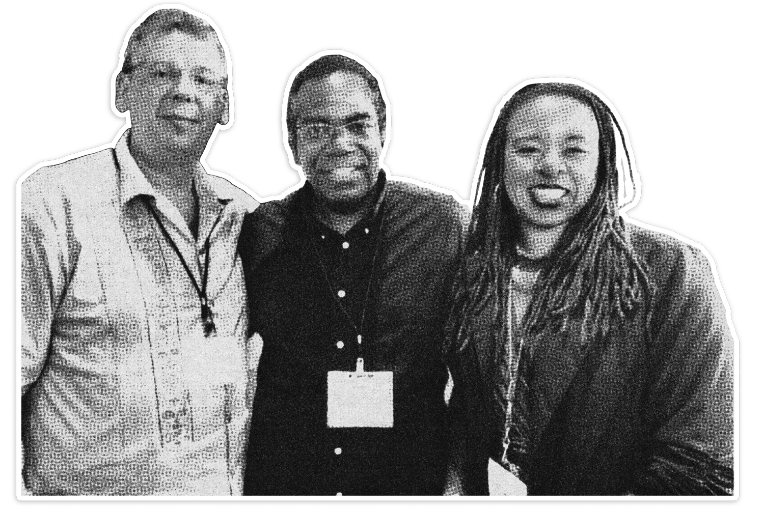 Black and white photo of three smiling people standing together, with a dark background. The person on the left is wearing a light-colored shirt, the person in the middle is wearing a dark shirt with a name tag, and the person on the right has long dreadlocks and is wearing a dark jacket.