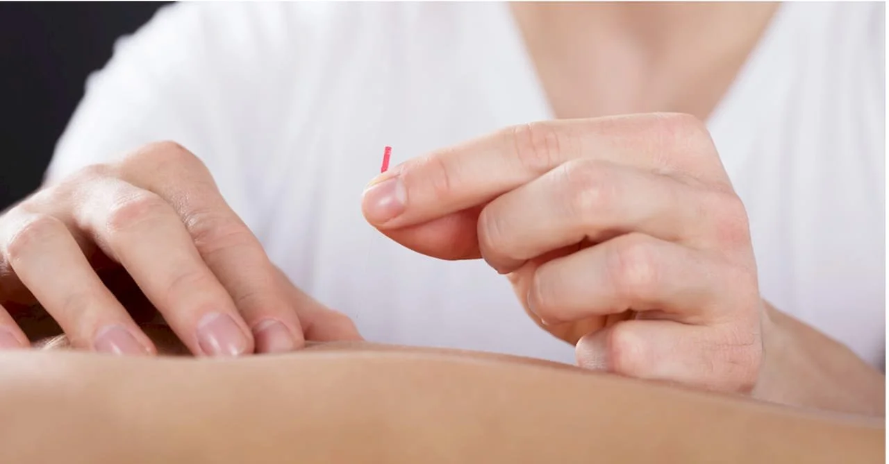 Persoon houdt een klein rood en wit elastiekje vast boven iemand anders huid.