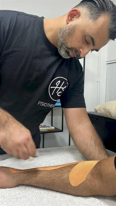 Fysiotherapeut die een patiënt behandelt met taping op de arm.