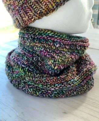 A colorful matched set of hand knit cowl and hat on a foam mannequin head