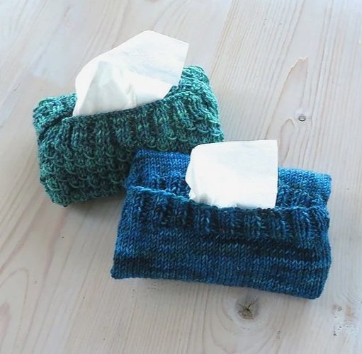 two hand knit tissue packet holders, one blue and one textured blue-green