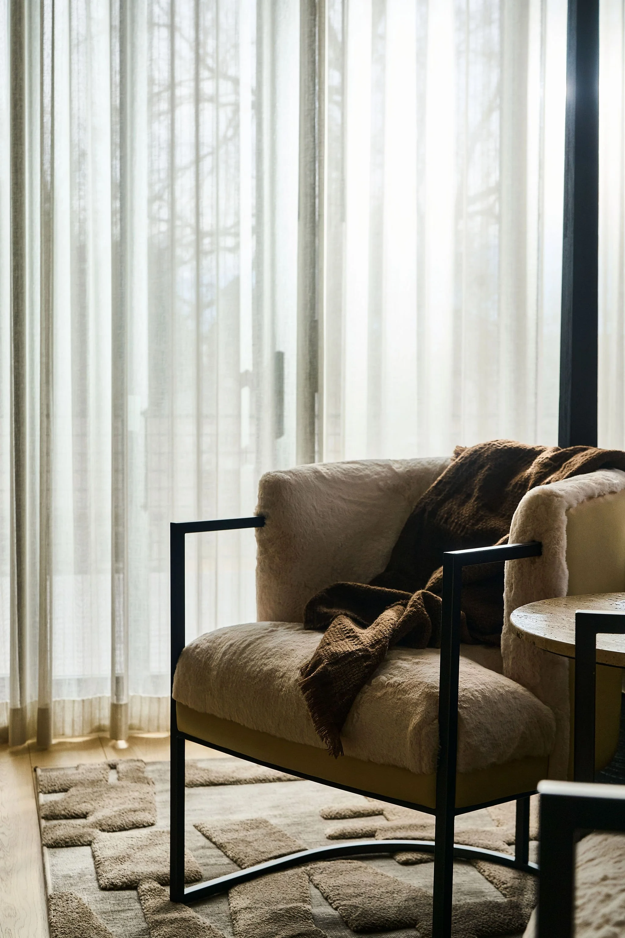 dreamy bedroom with sheer drape and textured fur chair with throw blanket