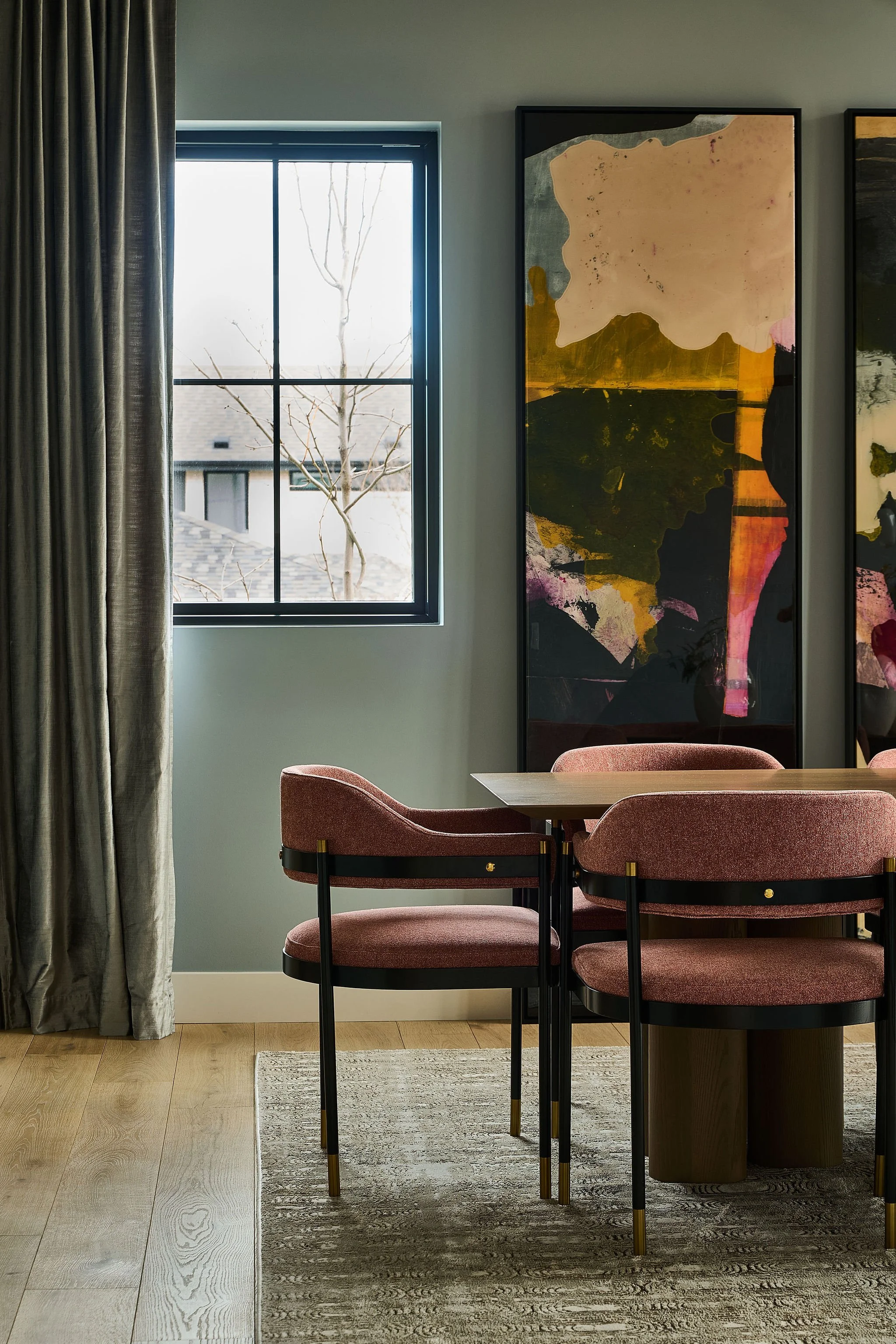 Dining room vignette with blush upholstered chairs and oversized modern artwork