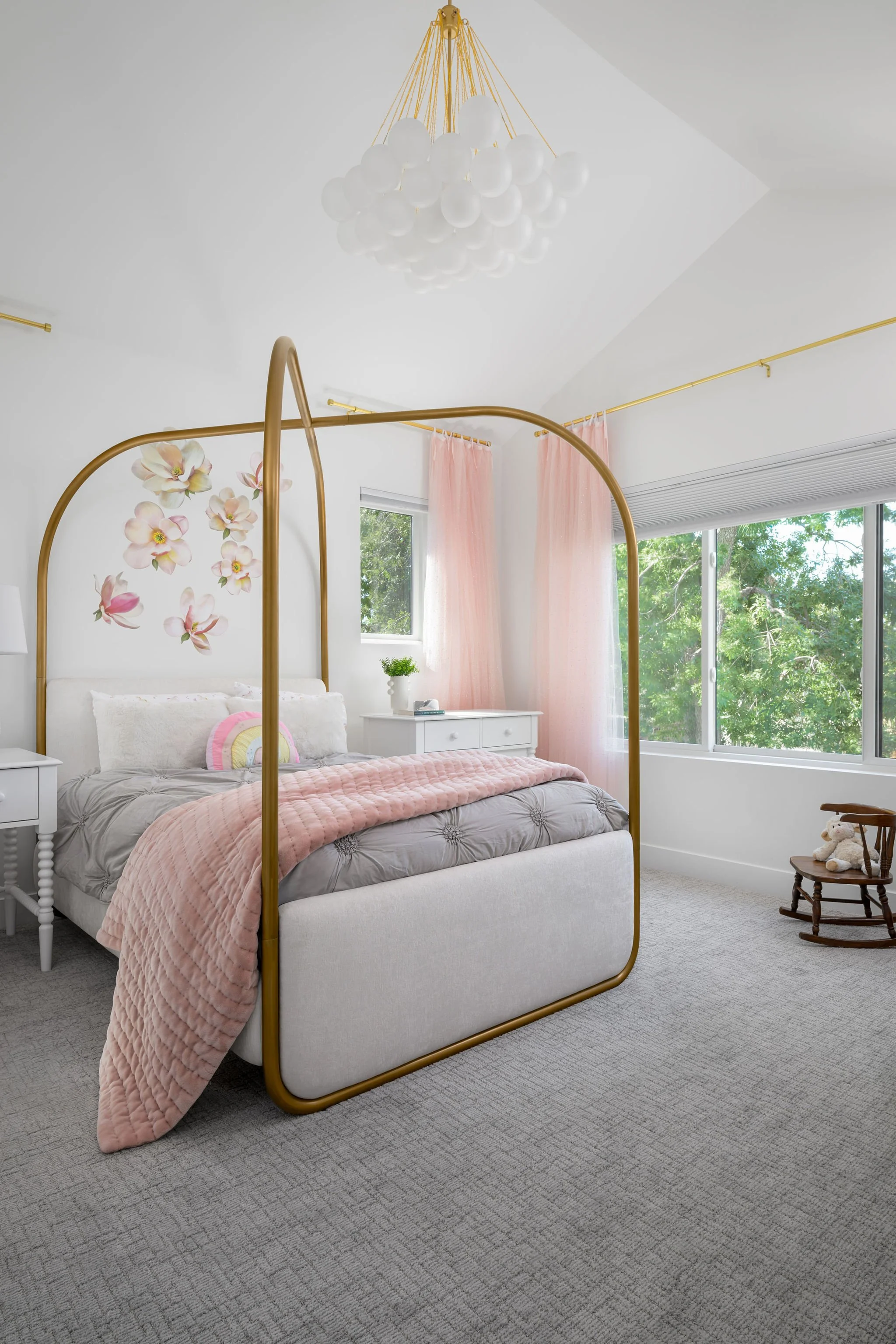 Modern girls bedroom in Denver featuring soft pink accents, brass canopy bed, layered textures, and thoughtful family-focused interior design.
