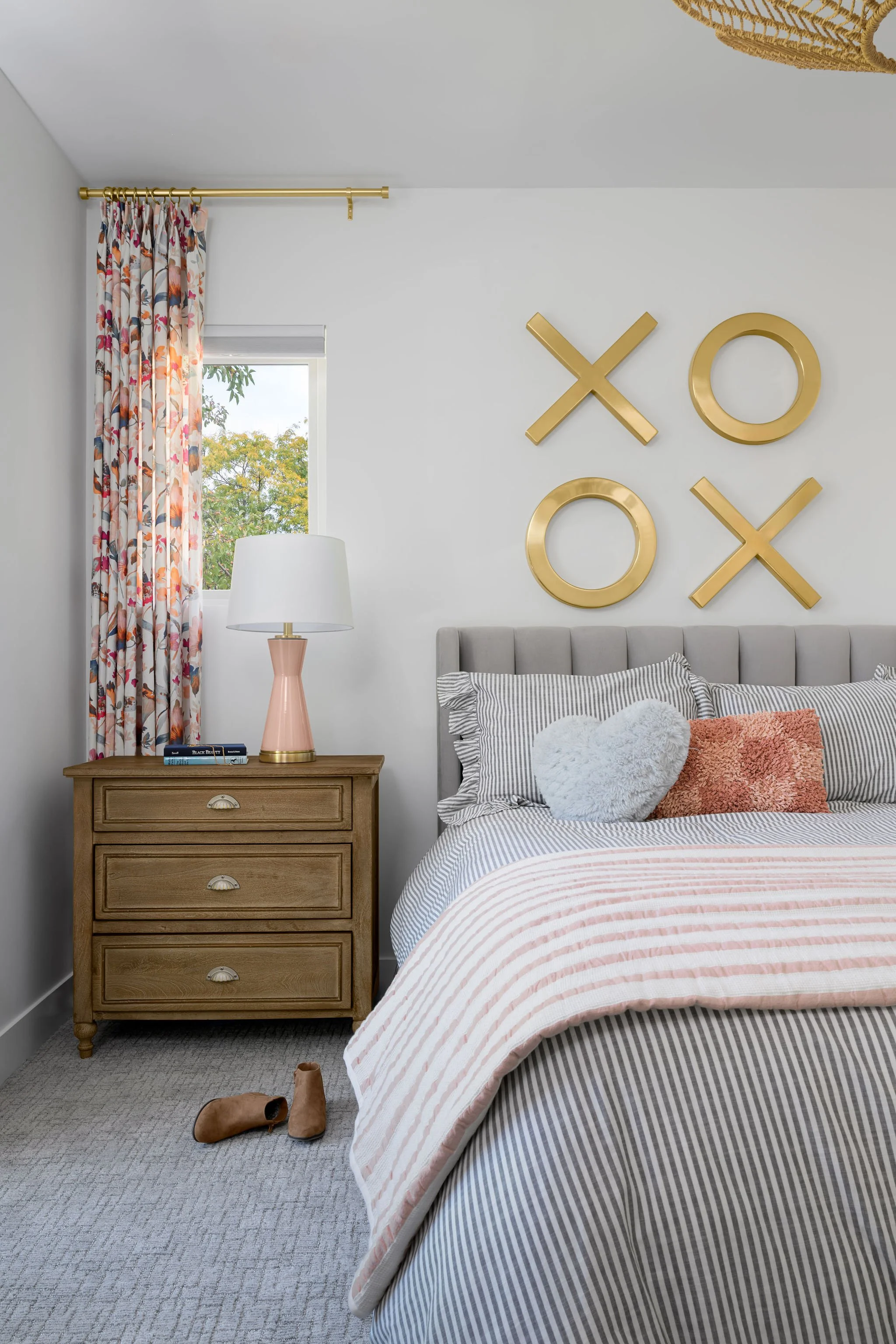 Modern girls bedroom in Denver featuring playful wall decor, layered neutral bedding, pink accents, and custom furnishings designed to grow with the family.