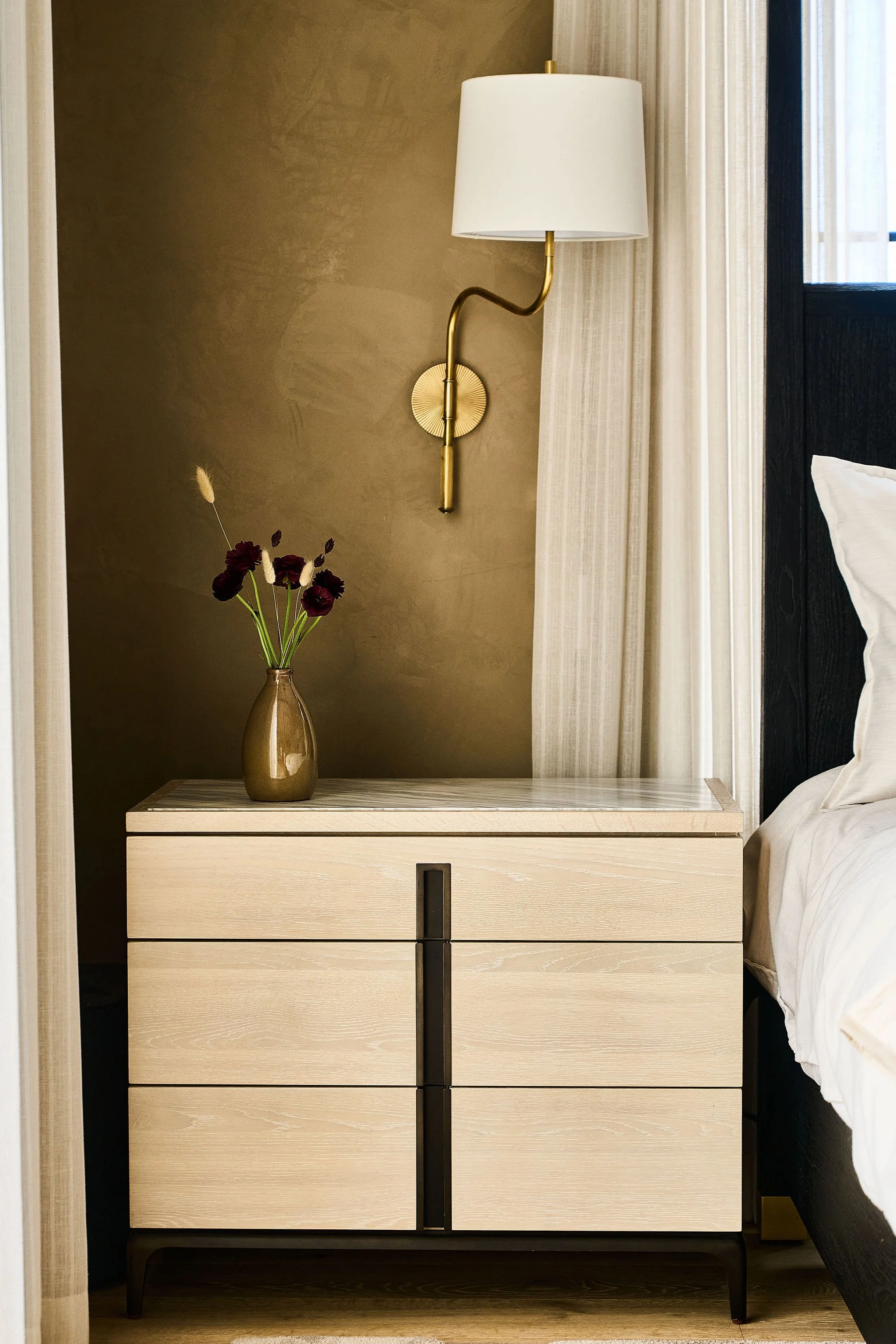 white oak nightstand styled against warm roman clay walls with brass sonce detail