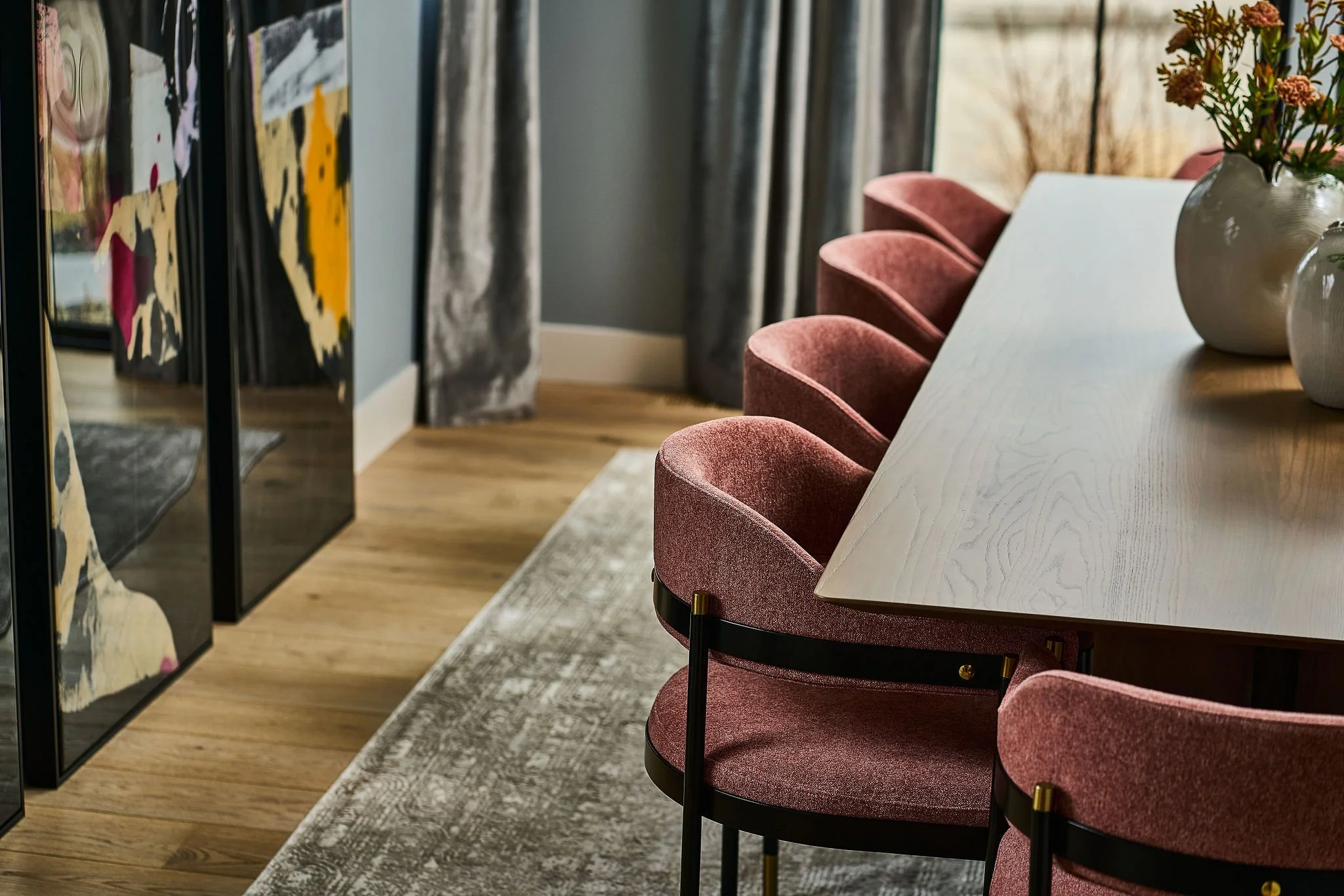 pink velvet dining chairs with modern artwork leaning on floor