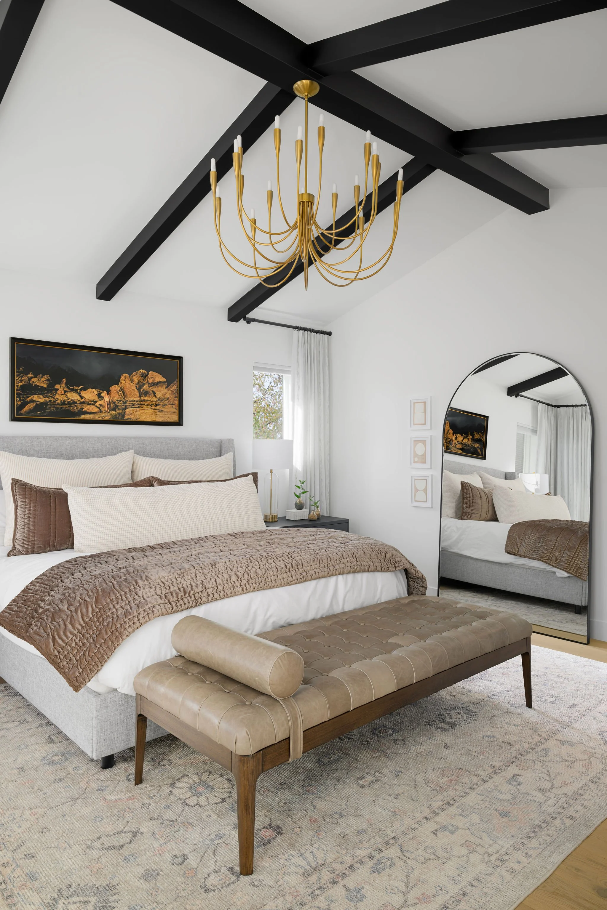 neutral primary bedroom with vaulted ceiling and black beams