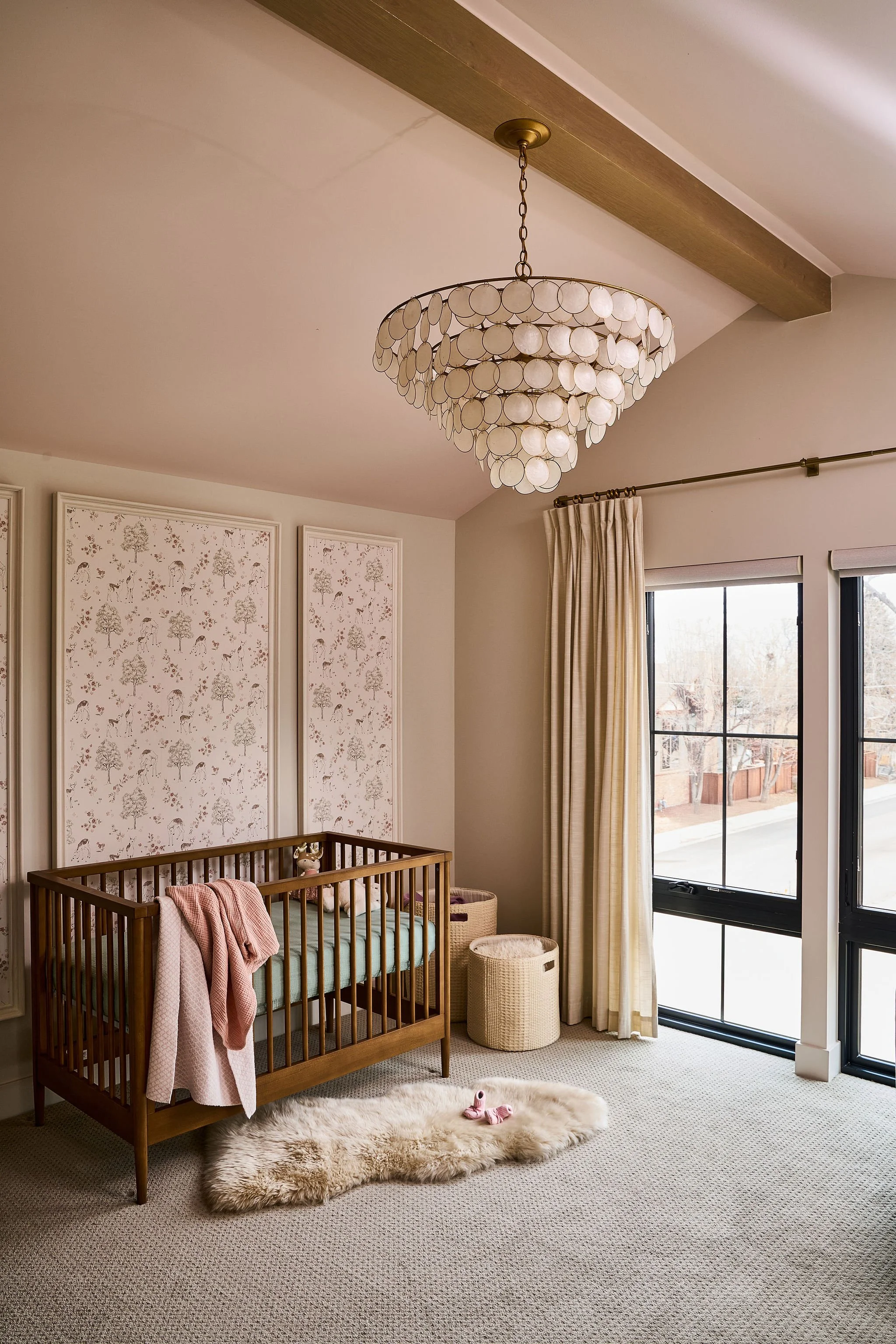 Feminine nursery with statement chandelier, warm neutral tones, and layered textures