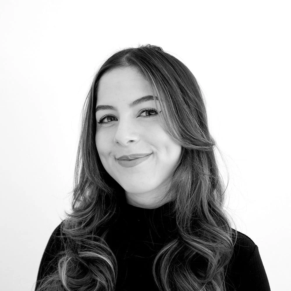 Black and white portrait of Stephanie Cruz smiling in a black high neck blouse