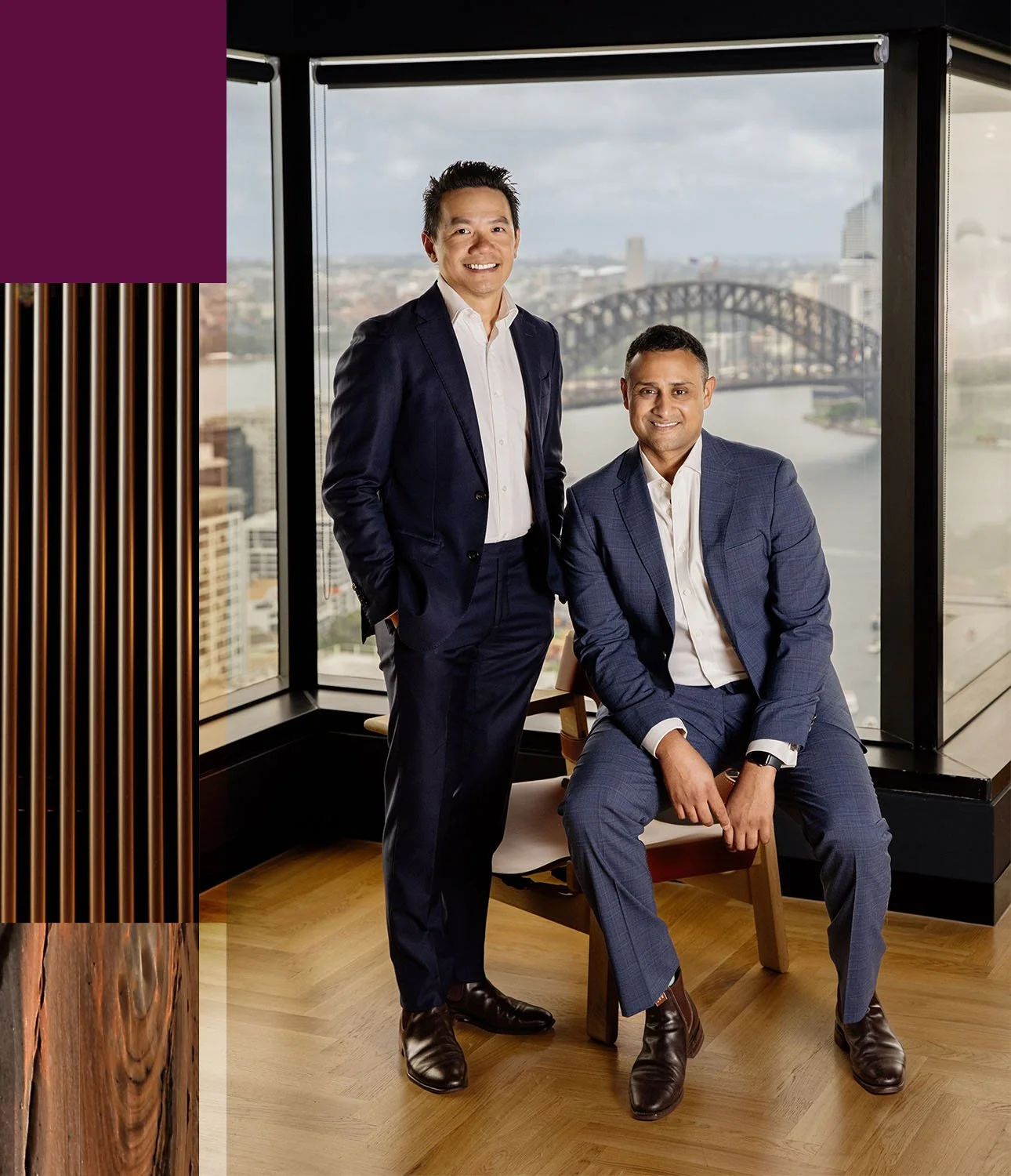 Founders Timothy Lee and Simran Dhillon dressed in suits in their office with the Sydney Harbour bridge behind them