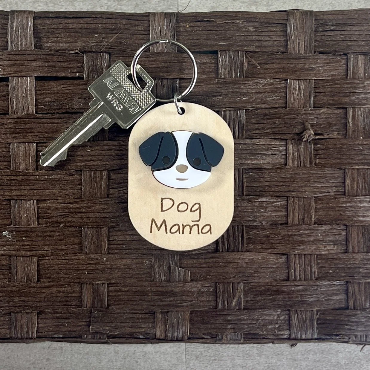 lifestyle shot of laser cut maple wood keychain with black/white dog face that says "Dog Mama"