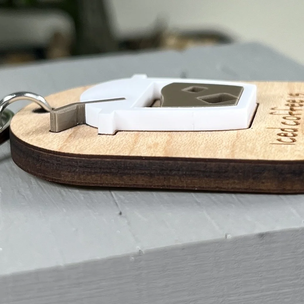 side view of laser cut maple keychain showing iced coffee graphic in raised matte white/espresso acrylic to highlight depth and texture of product.