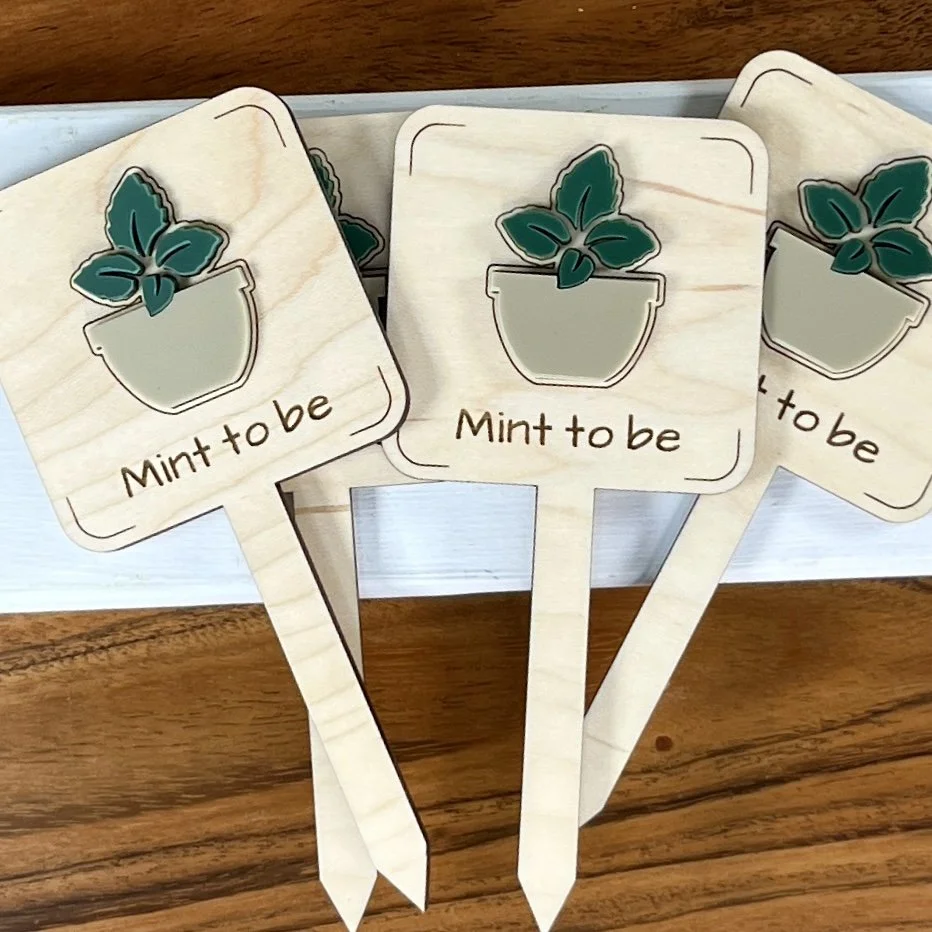 flat lay maple plant stake featuring a potted mint plant embellishment engraved with the phrase "Mint to be".