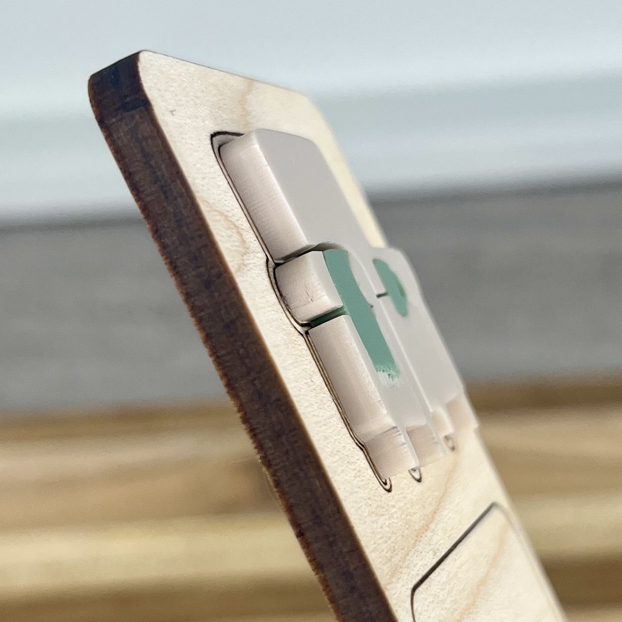 angled view maple bookmark featuring a comfy sand coloured acrylic chair with sage blanket and coffee mug embellishment engraved with the phrase "Introverting with books".