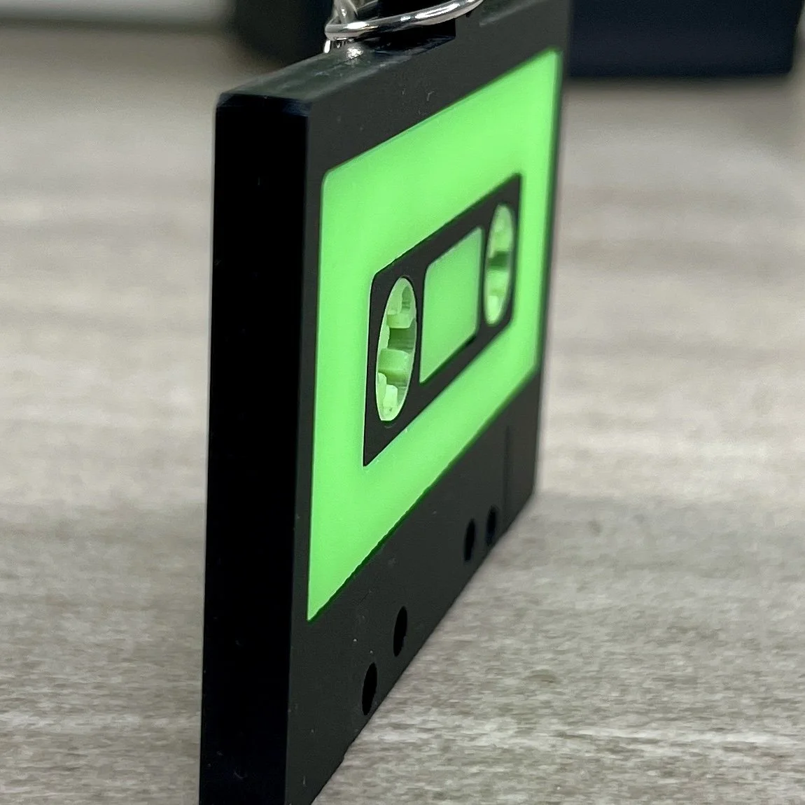 Side view of retro cassette tape-shaped acrylic backpack tag highlighting the depth and texture of the product..
