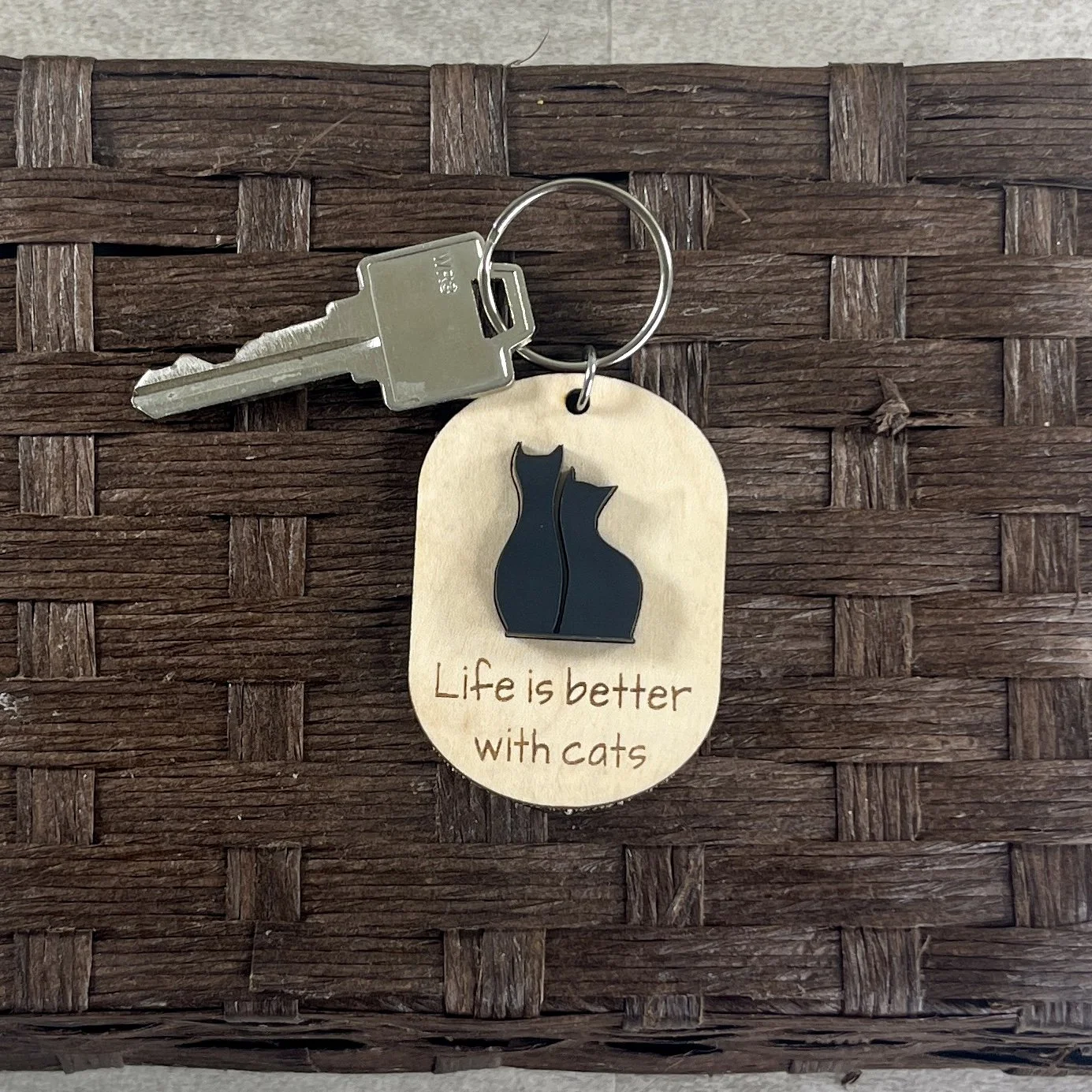 handheld laser cut maple wood keychain with silhouette of two cats in matte black acrylic and saying "Life is better with cats".