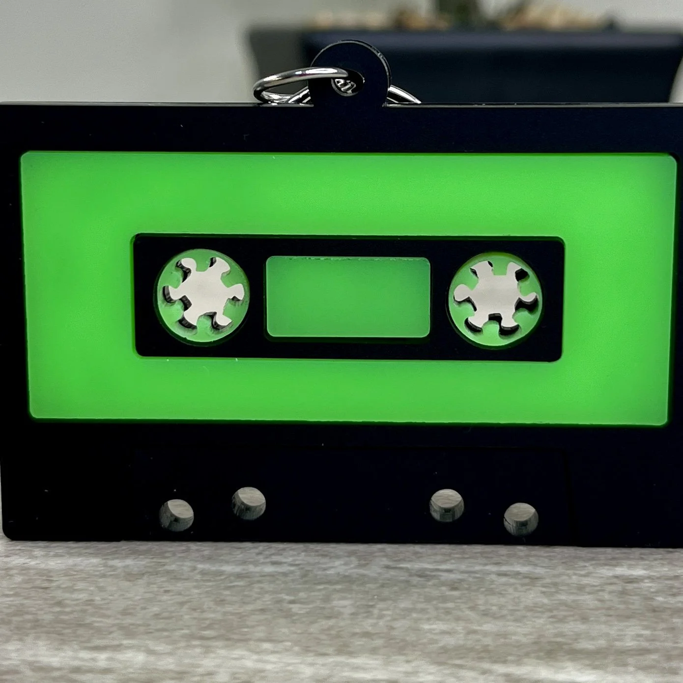 Close up of retro cassette tape-shaped acrylic keychains in radioactive green.