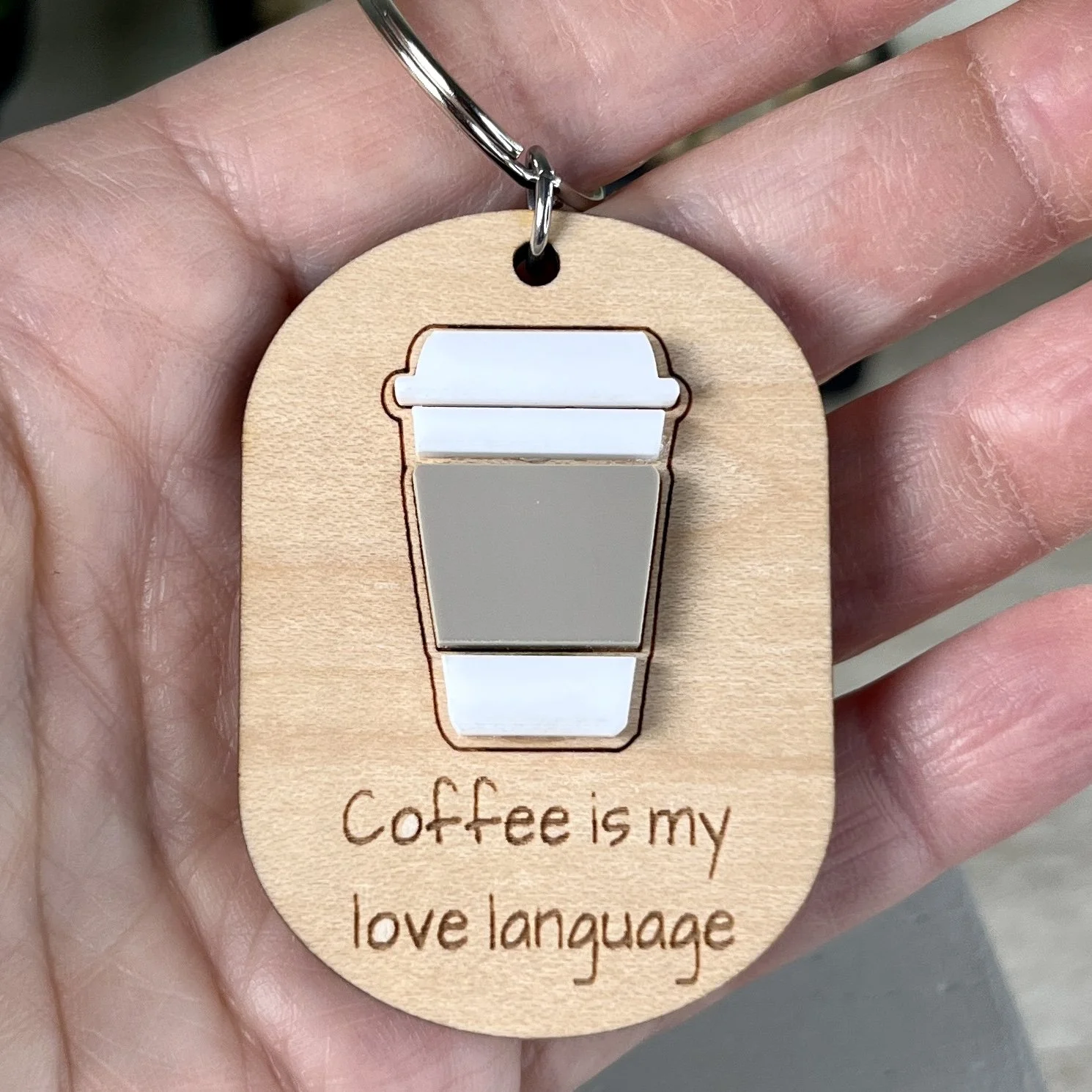 handheld laser cut maple keychain showing coffee cup graphic in raised matte white/espresso acrylic and engraved with "Coffee is my love language".