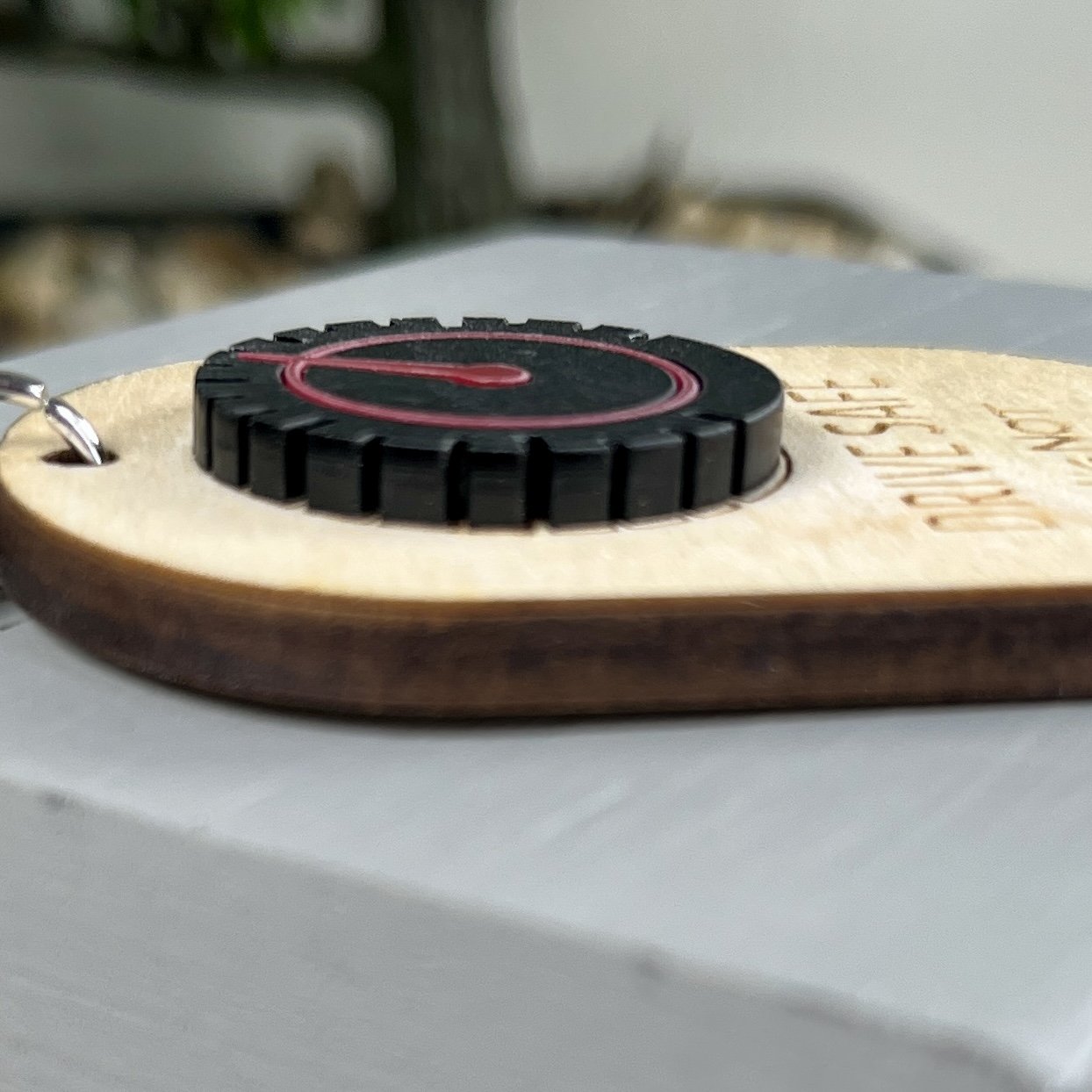 side view of laser cut maple wood keychain with speedometer in matte black/red acrylic highlighting the depth and texture of the product.