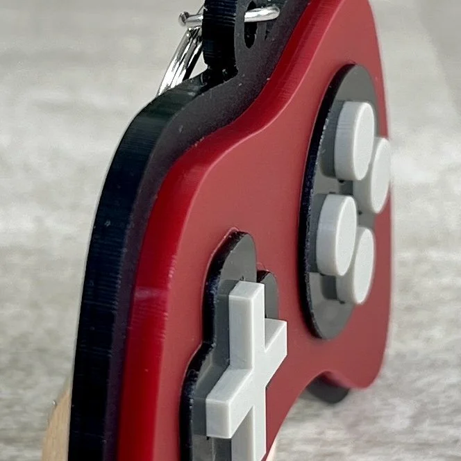 Side view of game controller-shaped acrylic backpack tag highlighting depth and texture of product.