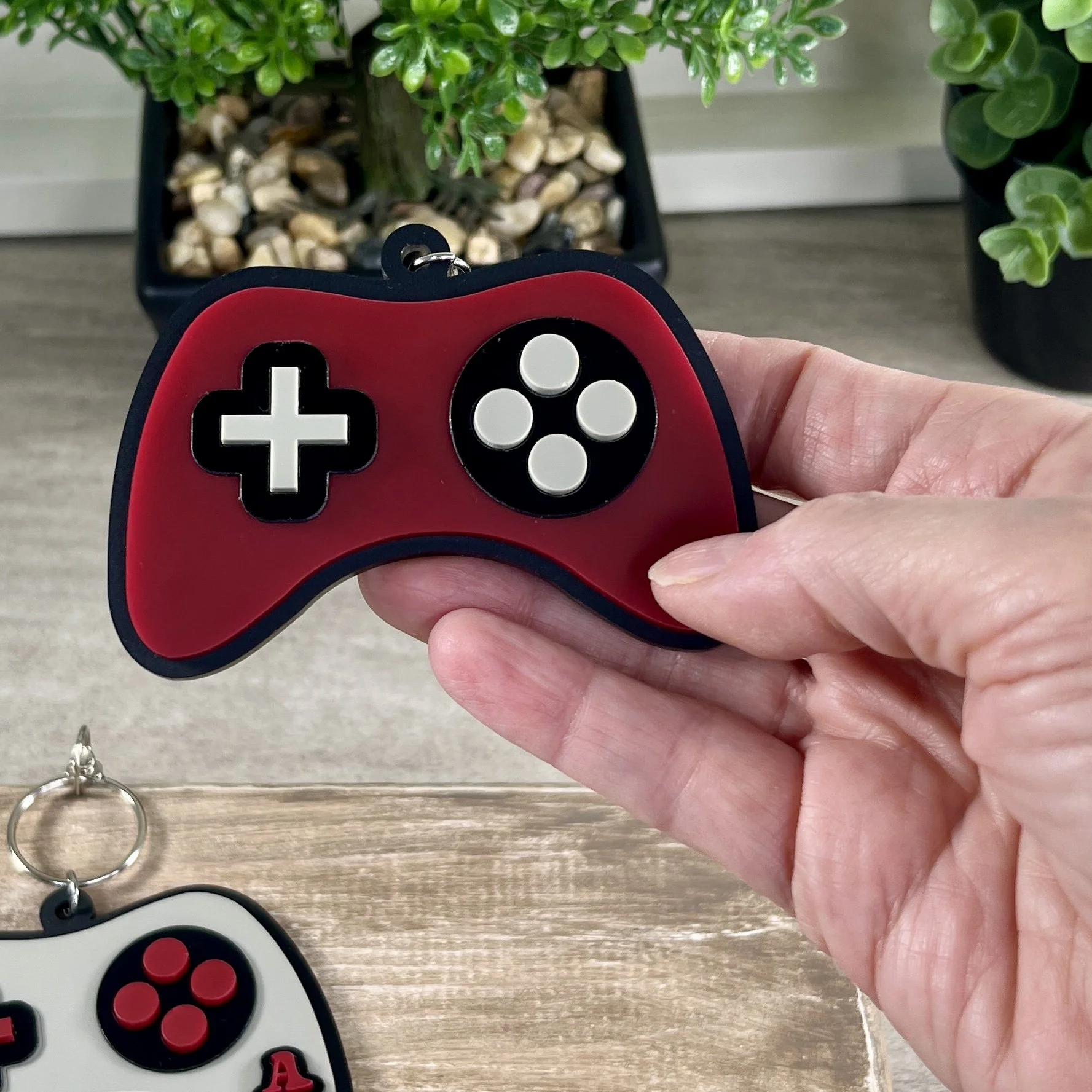Game controller-shaped acrylic backpack tag held in hand for scale.