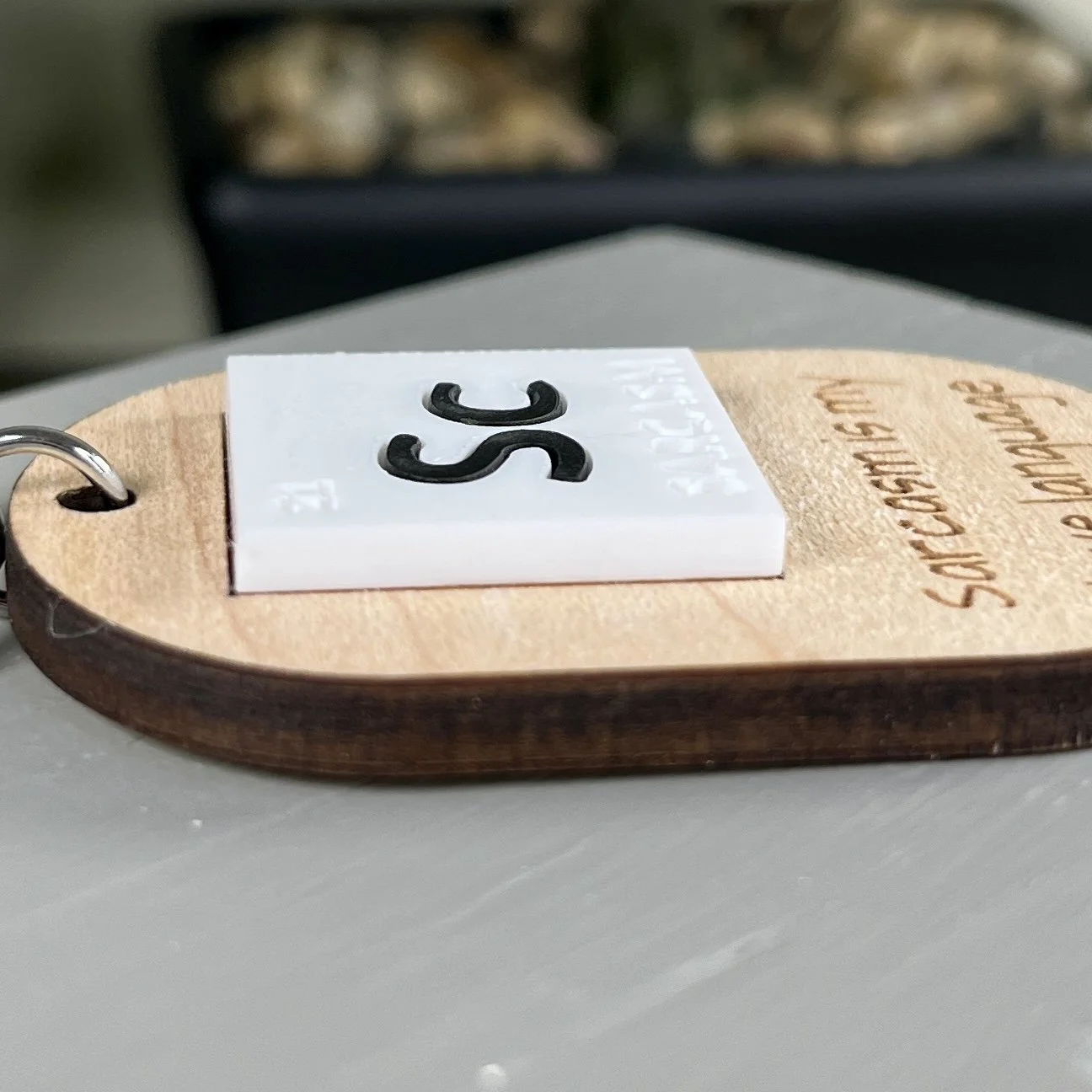 side view of maple wood keychain with a periodic table-inspired acrylic tile reading "Sc" for Sarcasm highlighting the dept and texture of the product.