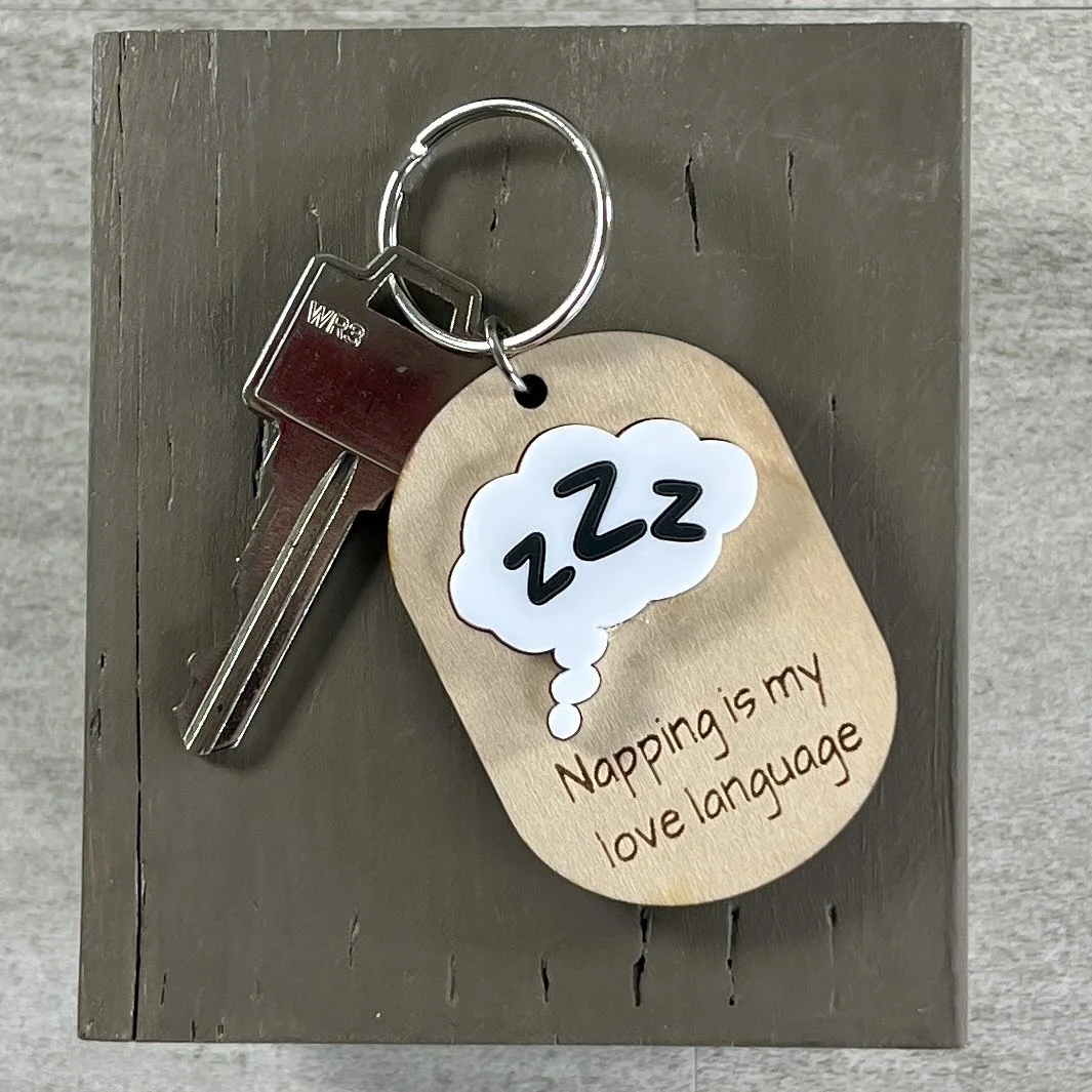 lifestyle shot of laser cut maple keychain with ZZZ in thought bubble in raised white/black matte acrylic and engraved with "Napping is my love language".