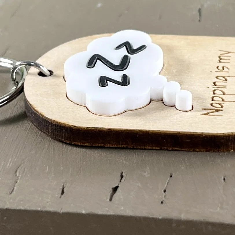 side view of laser cut maple keychain with ZZZ in thought bubble in raised white/black matte acrylic highlighting depth and texture of product.