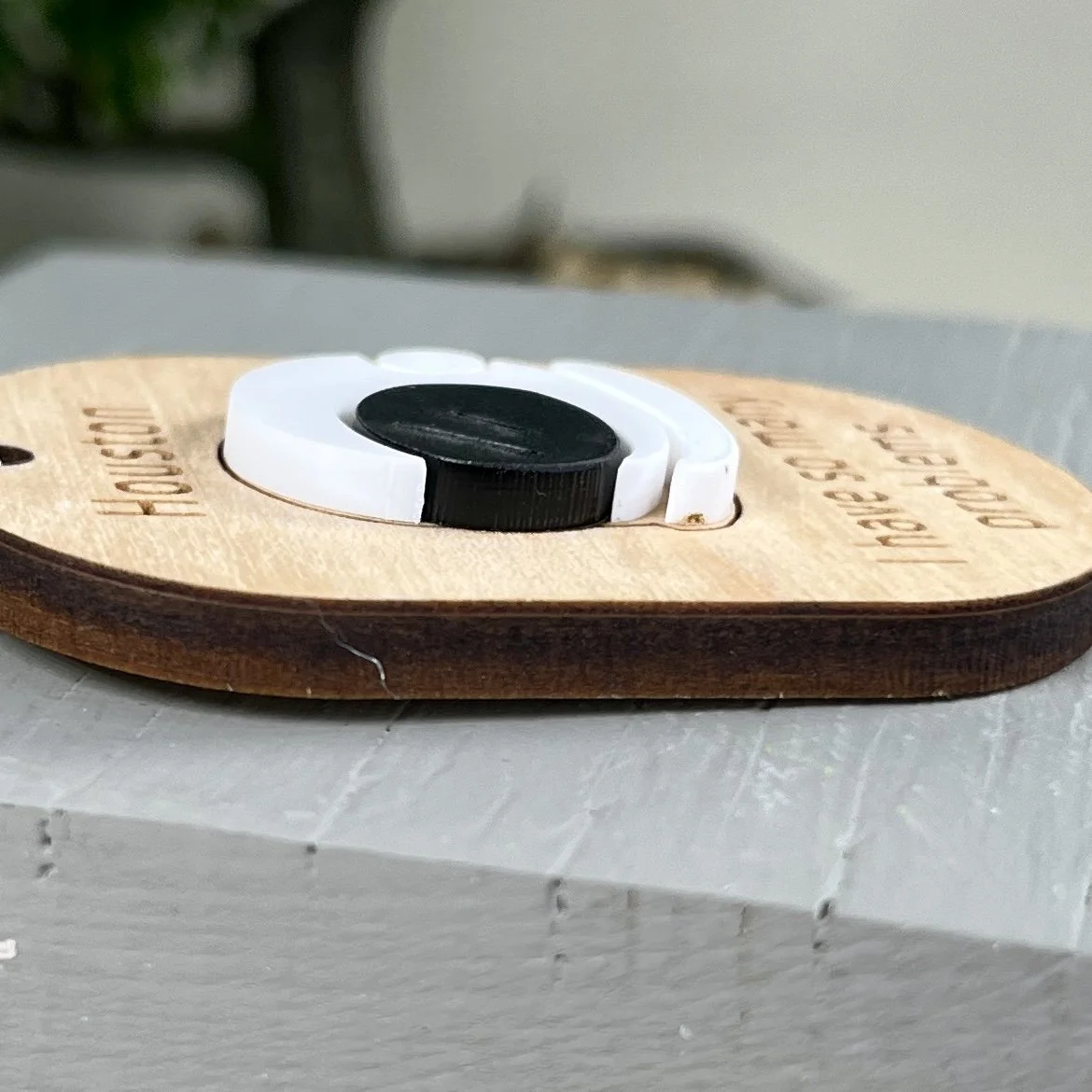 side view of laser cut maple keychain showing astronaut helmet graphic in raised matte white/black acrylic to highlight the depth and texture of the product.