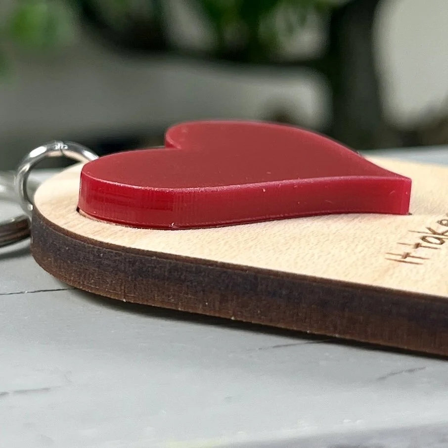 side view of laser cut maple wood keychain featuring raised matte red acrylic heart highlighting depth and texture of product.