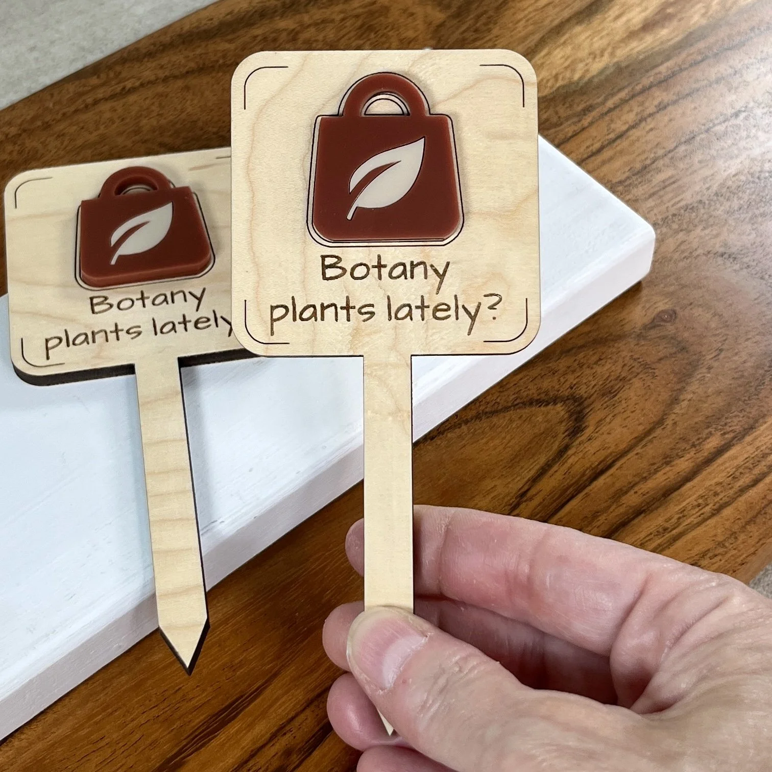 handheld maple bookmark featuring an acrylic garden centre shopping bag embellishment engraved with the phrase "All my friends are dead".