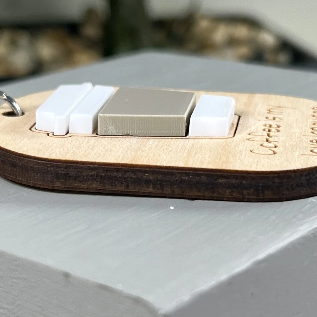 side view of laser cut maple keychain showing coffee cup graphic in raised matte white/espresso acrylic to highlight depth and texture of product.