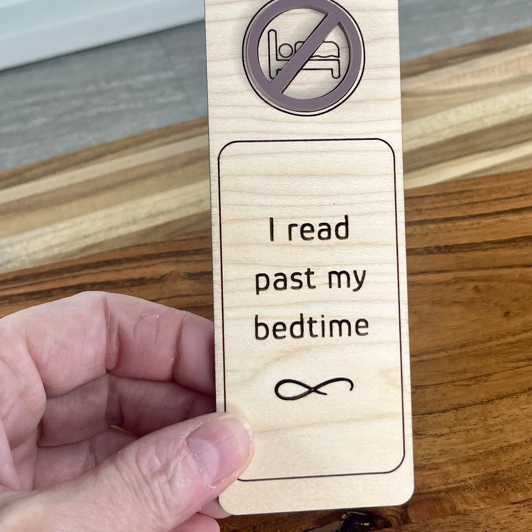handheld maple bookmark featuring a mauve no bedtime symbol embellishment engraved with the phrase "I read past my bedtime".