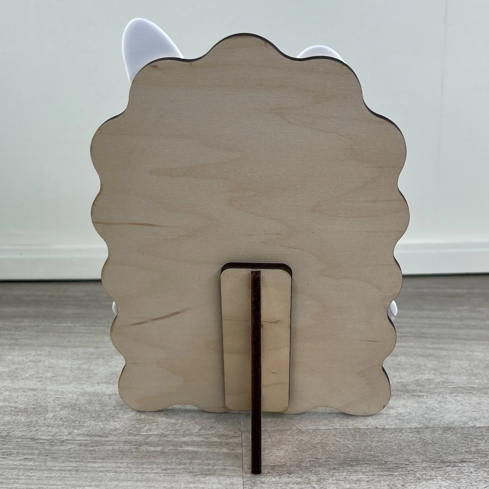 Back view of a maple wood Baby's First Easter photo frame with built-in stand and white acrylic bunny ears visible from behind.