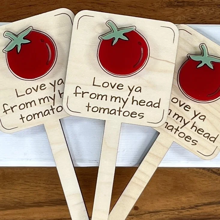 flat lay maple plant stake featuring a plump red tomato embellishment engraved with the phrase "Love ya from my head tomatoes".