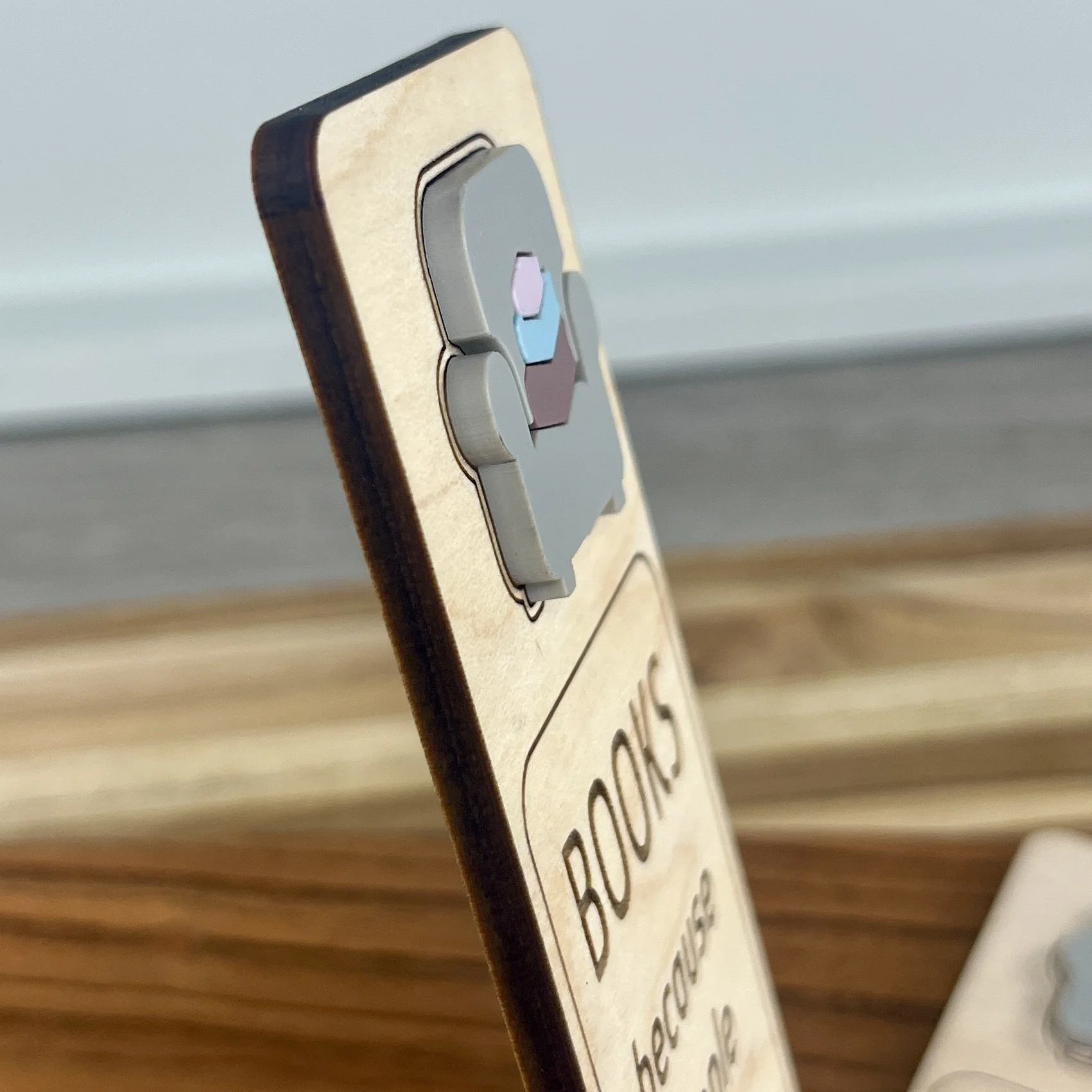 angled view maple bookmark featuring blue acrylic reading chair and stack of books embellishment engraved with the phrase "Books Because People Are Overrated".