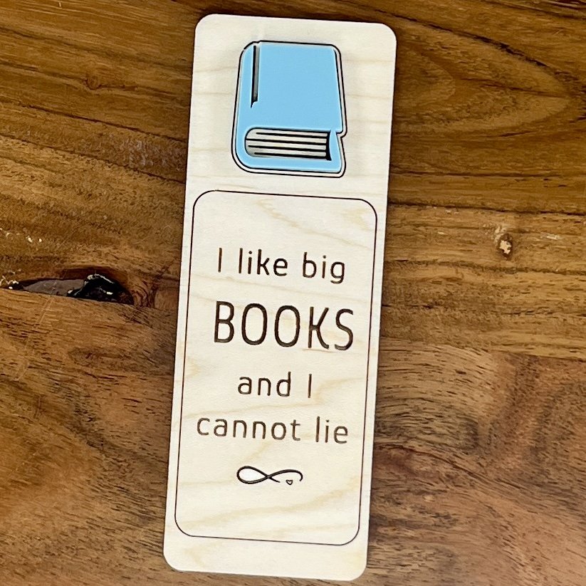 flat lay maple bookmark featuring an acrylic book engraved with the phrase "I like big books and I cannot lie”.