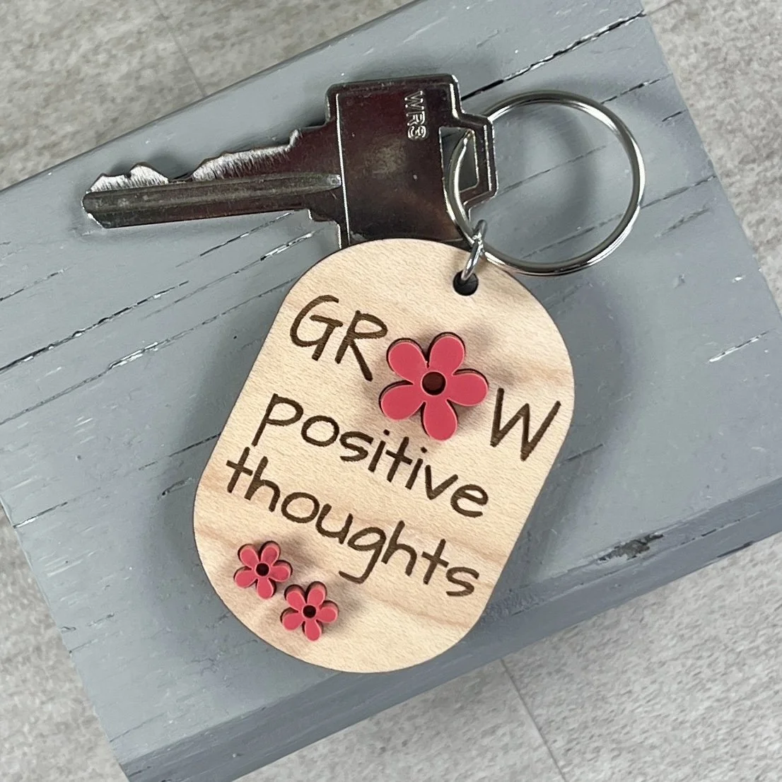 lifestyle shot of laser cut maple wood keychain with 3 matte acrylic watermelon coloured flowers grow positive thoughts gift Canada.